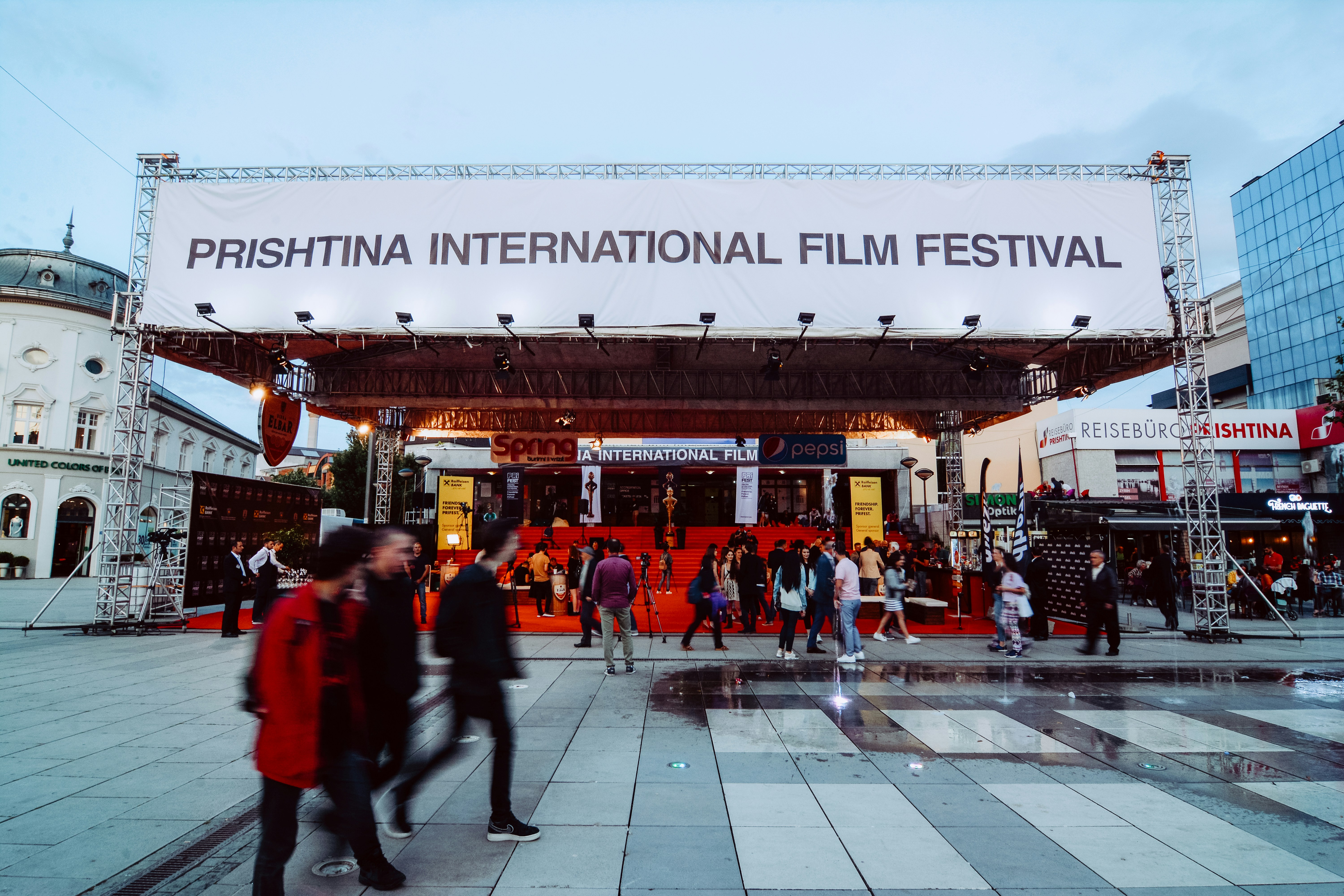 Menschen, die an einem großen Banner des Prishtina International Film Festival im Kosovo vorbeigehen.
