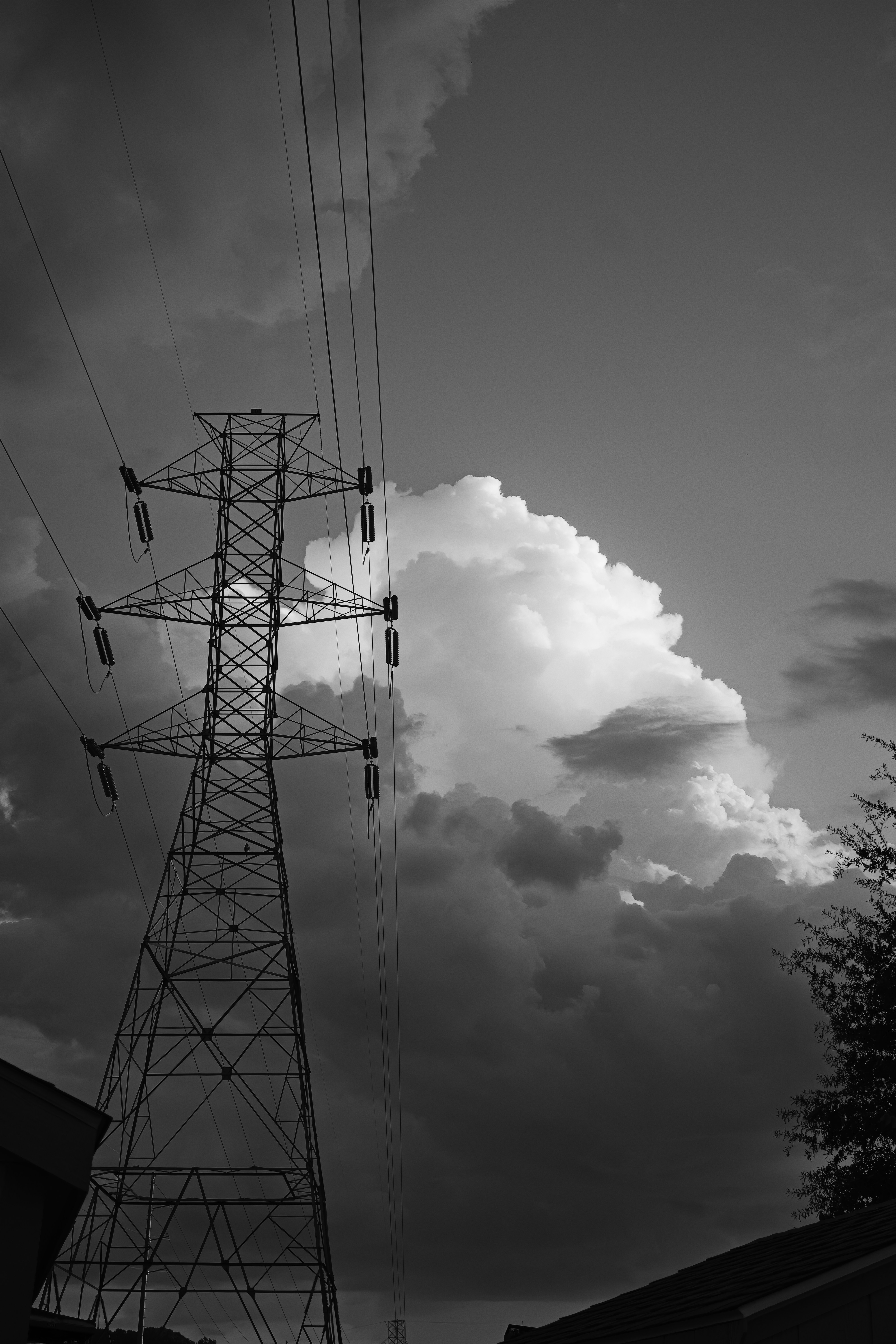 A tall metal electricity pylon silhouetted against a sky filled with large storm clouds