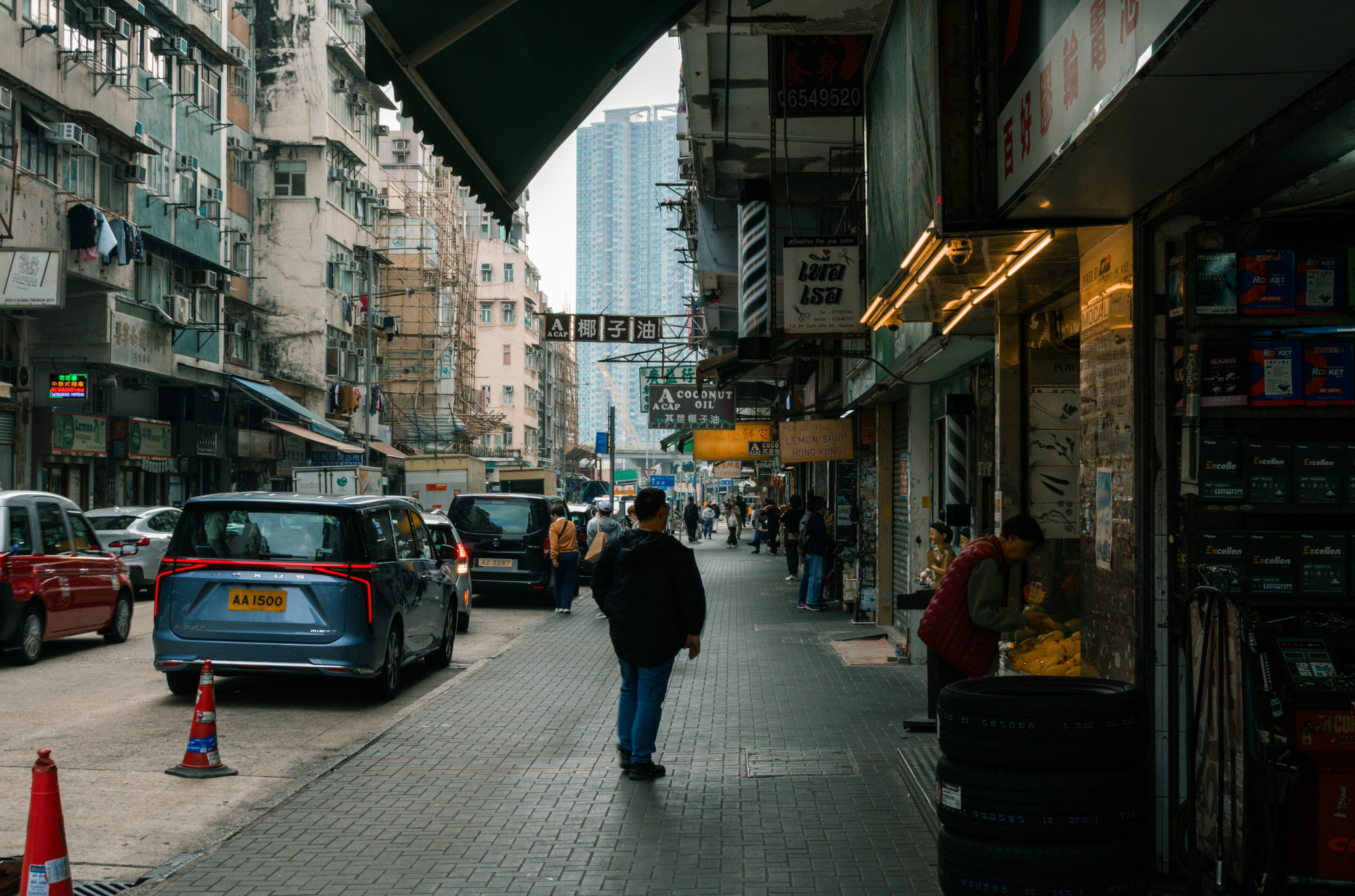 Eine belebte Straße in Hongkong mit Autos, Fußgängern und dichter Stadtarchitektur.