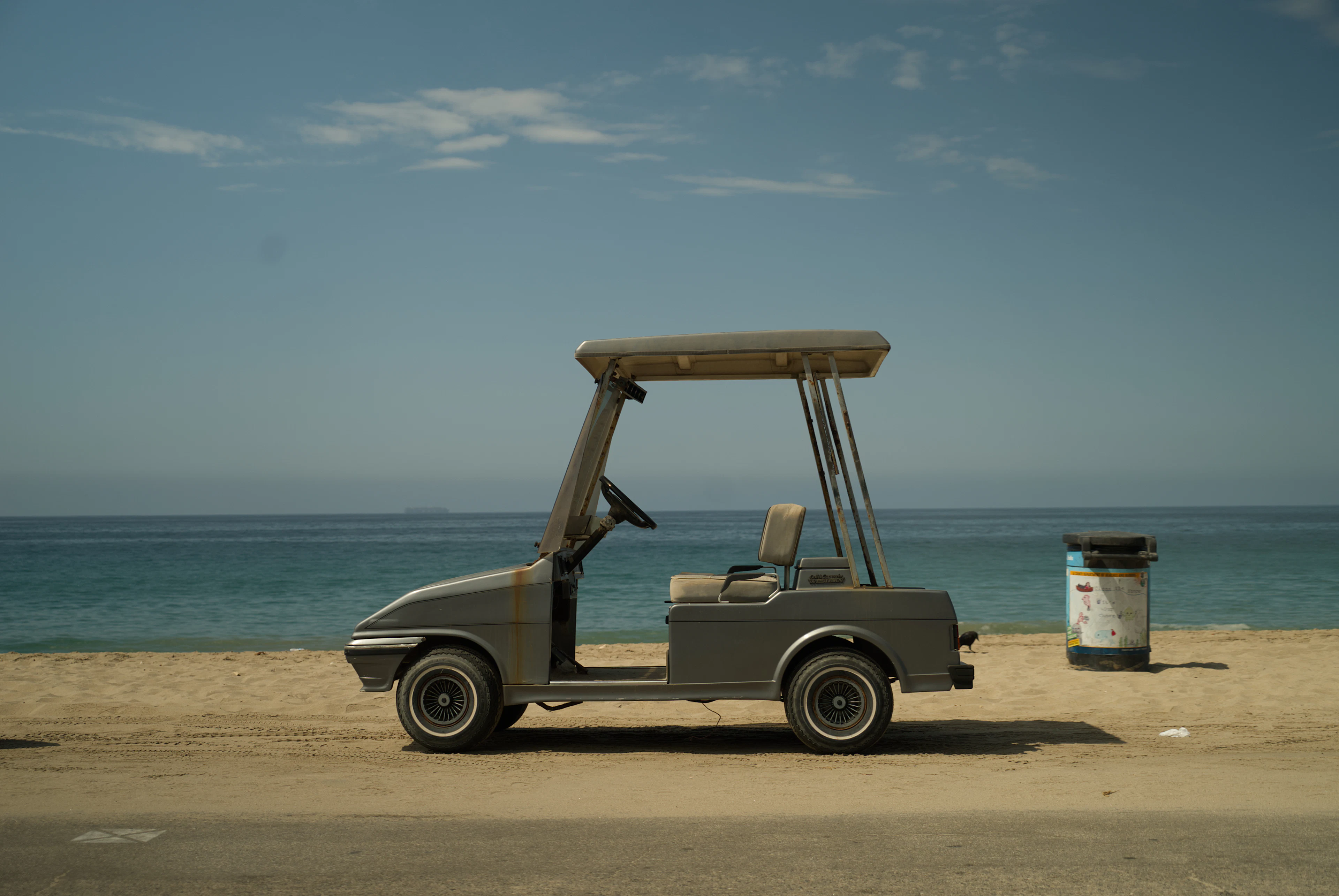 Golf cart parked on a sandy beach by the ocean