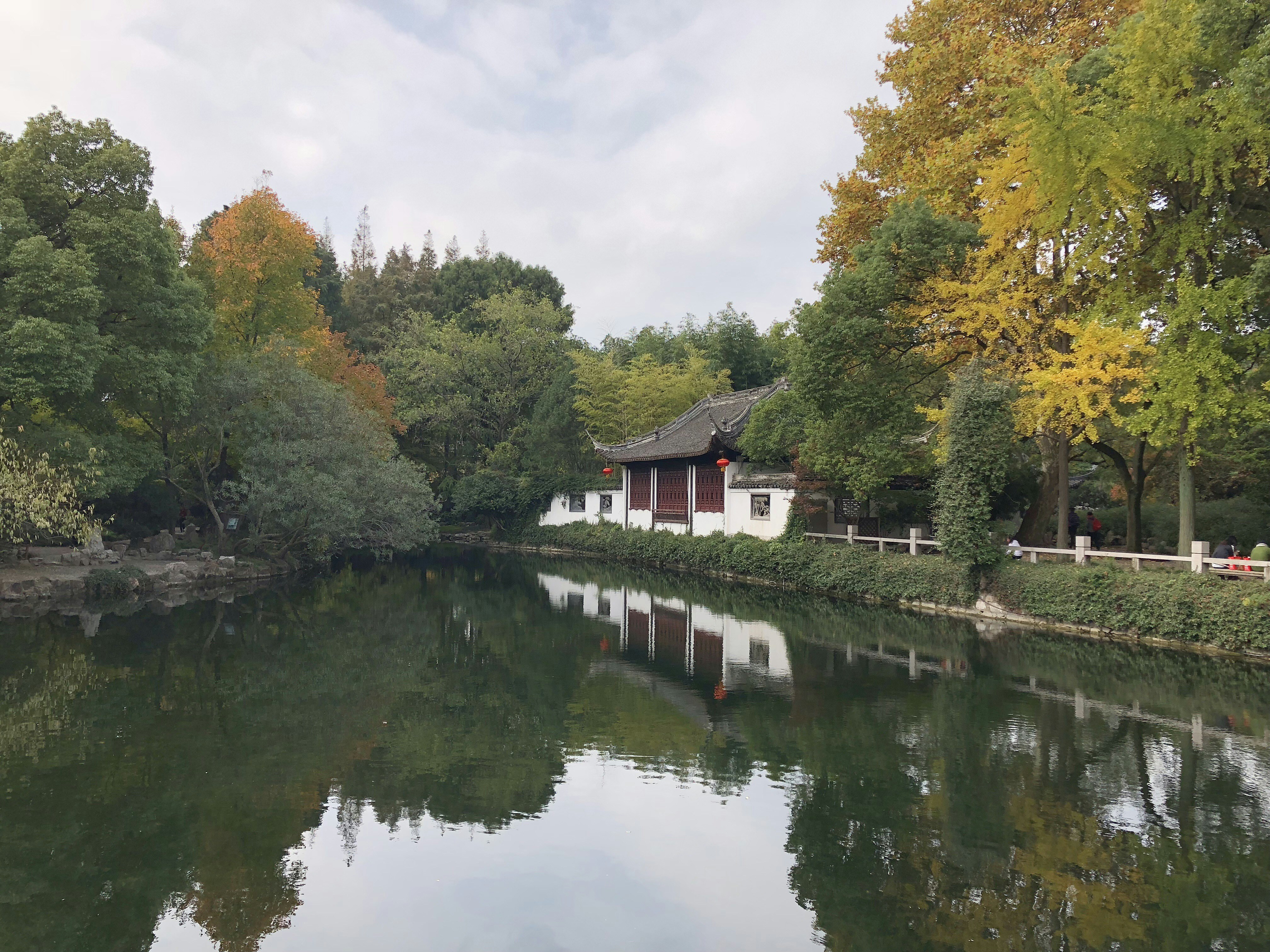 A traditional Chinese building reflected in a calm pond surrounded by autumn trees