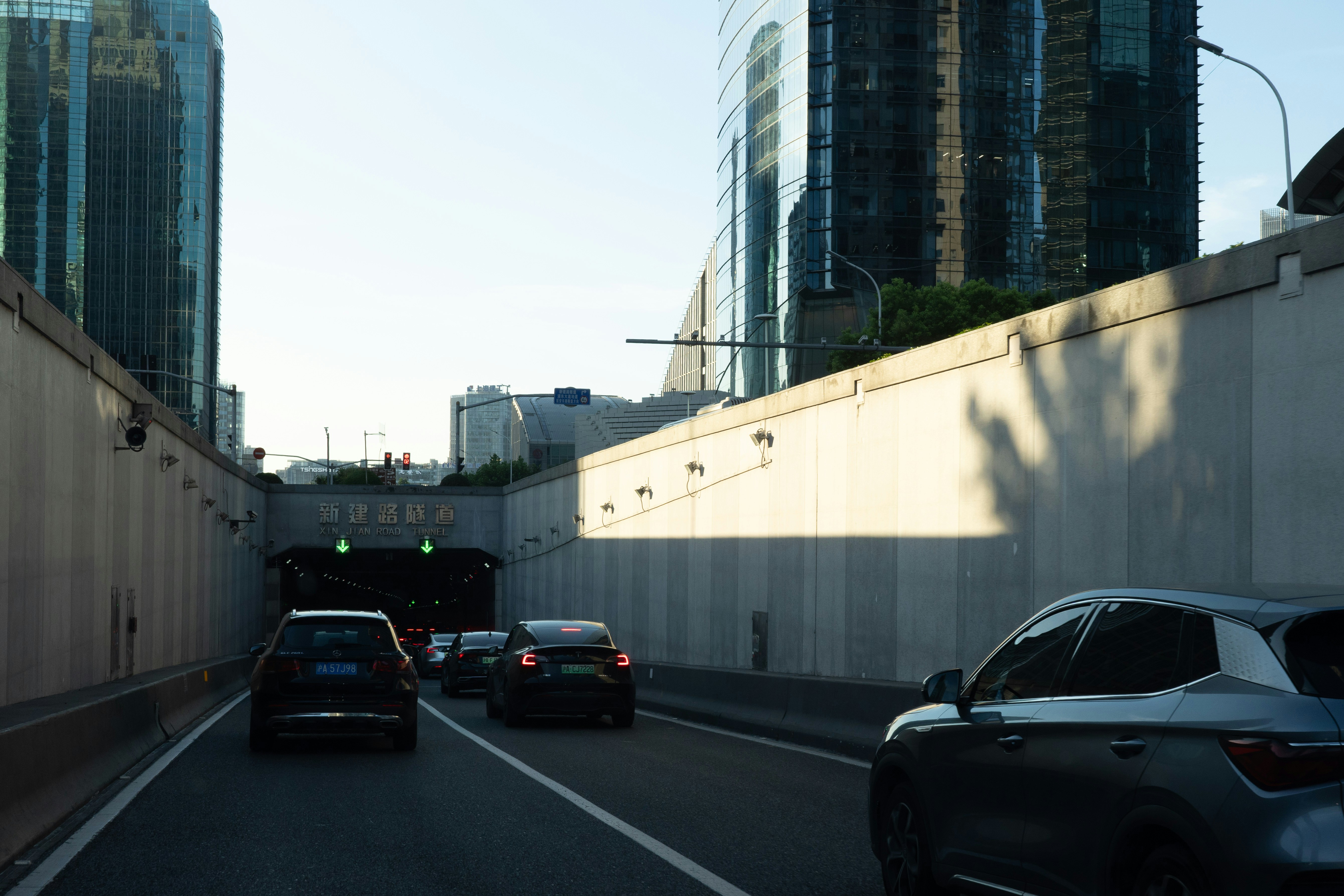 Cars entering the Xinjian Road Tunnel beneath modern skyscrapers in Shanghai.