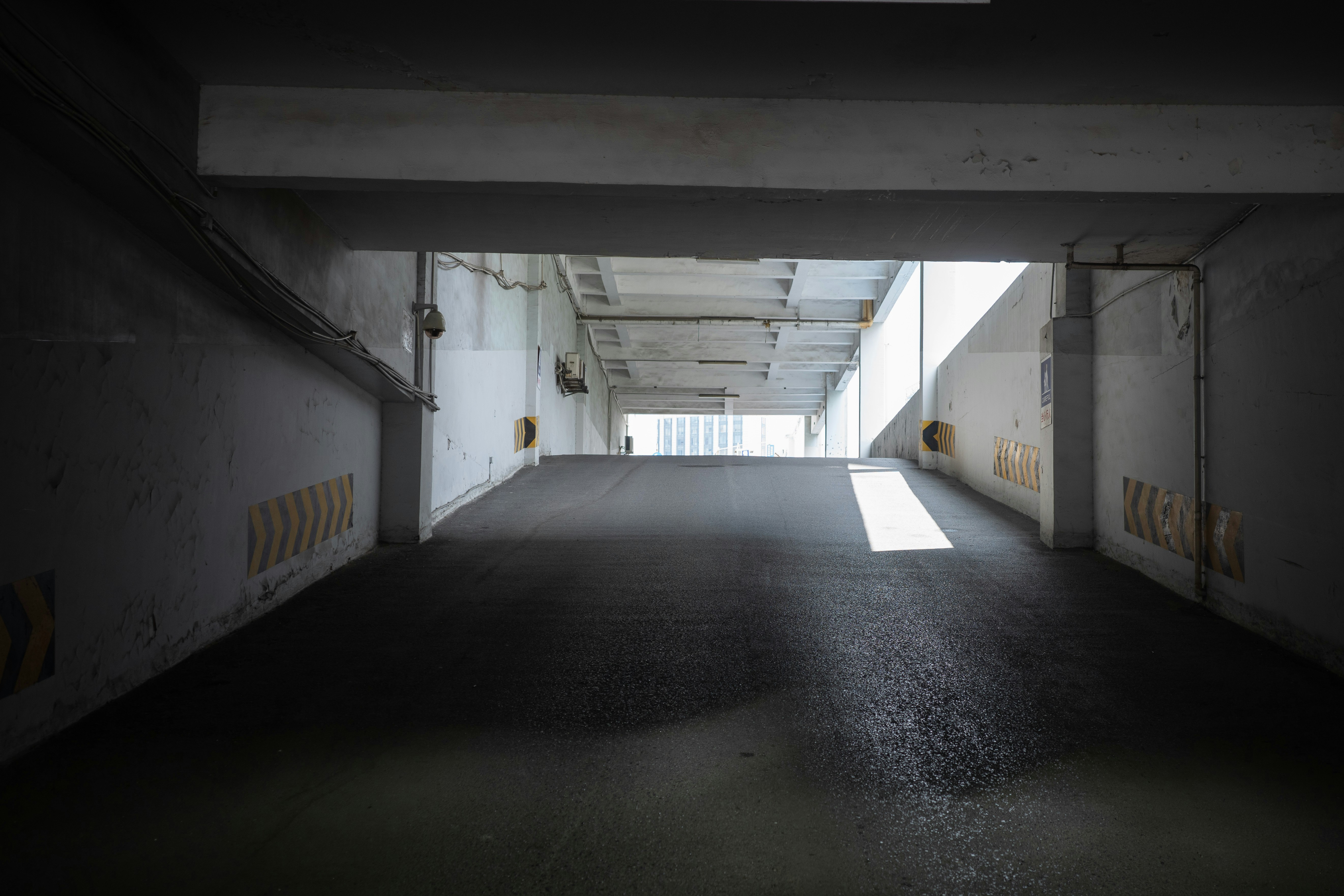 A concrete parking garage ramp with yellow and black hazard markings on the walls.