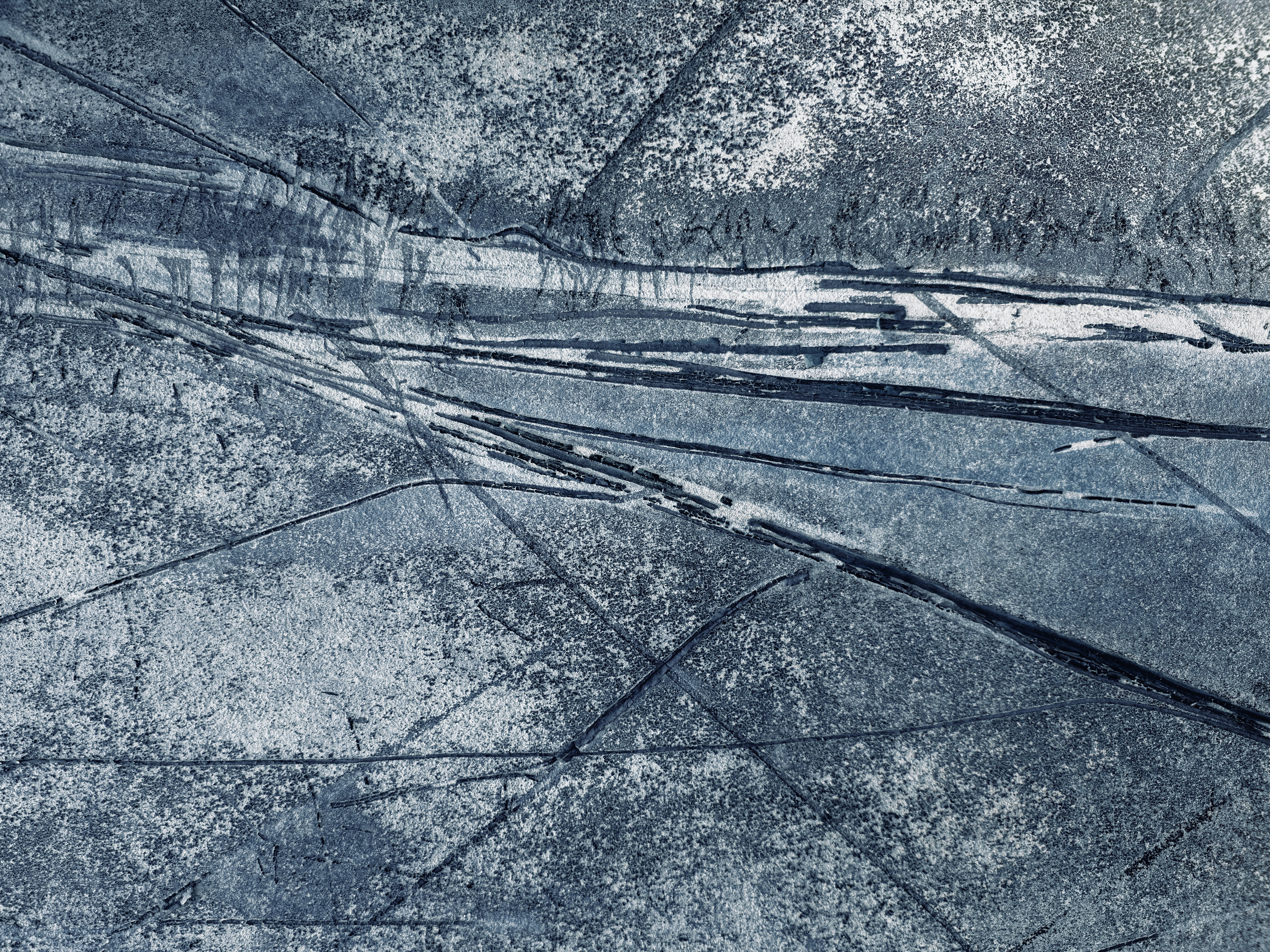 Dark blue textured surface with intersecting linear indentations and scratches.