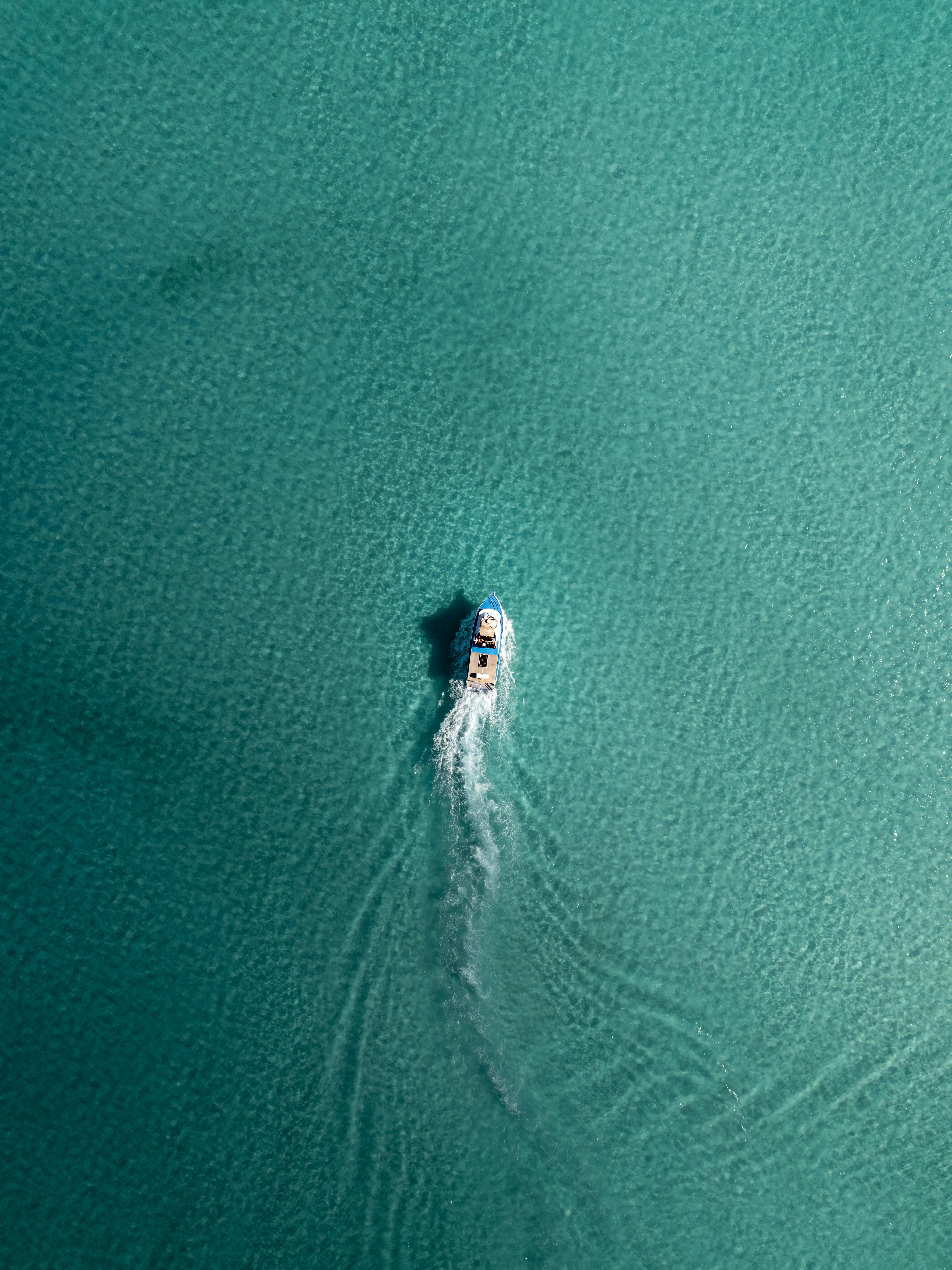 A small motorboat moving through clear turquoise water leaving a white wake