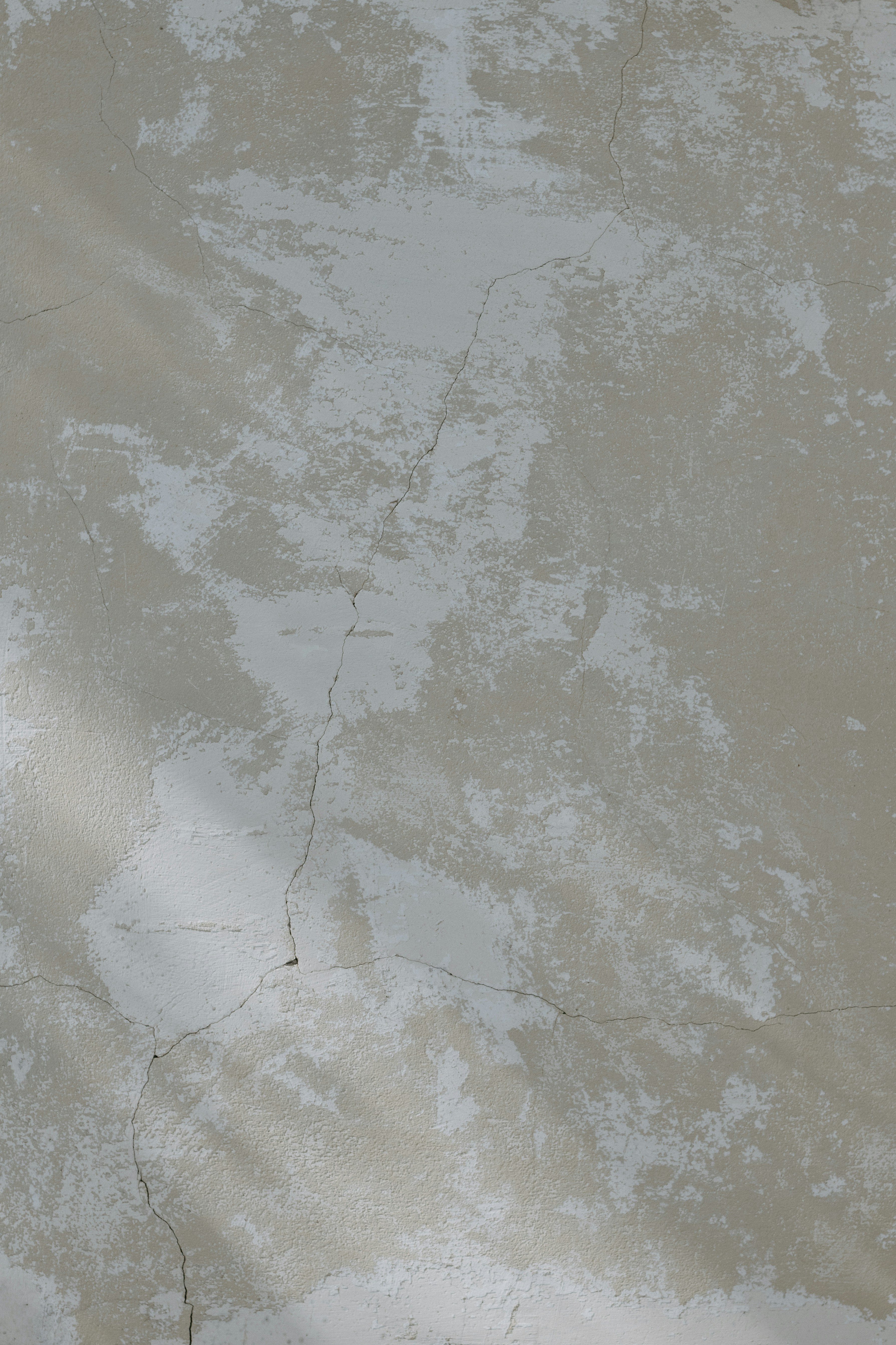 A weathered beige wall with peeling paint and visible cracks.
