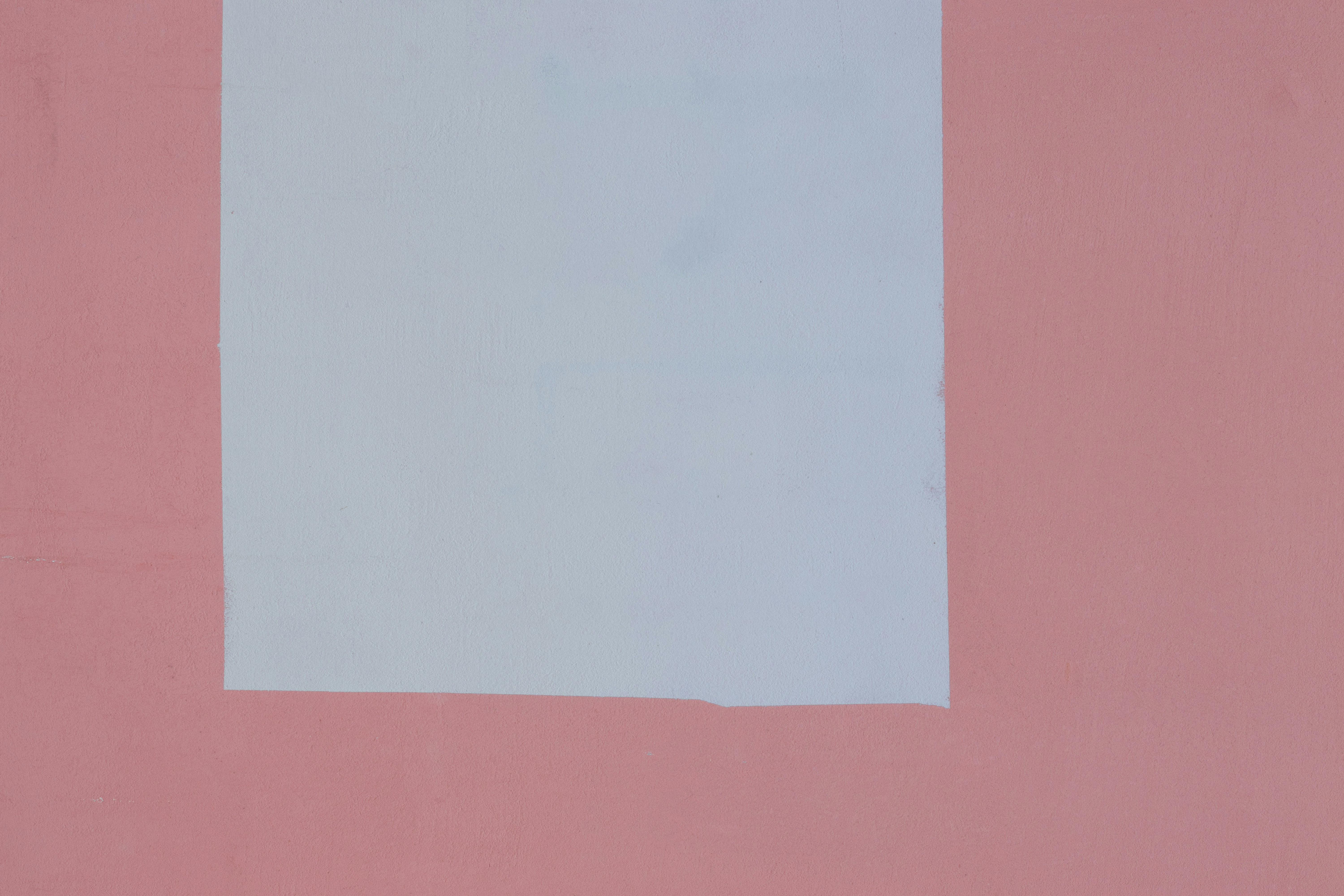 A large white rectangle painted on a solid pink wall.