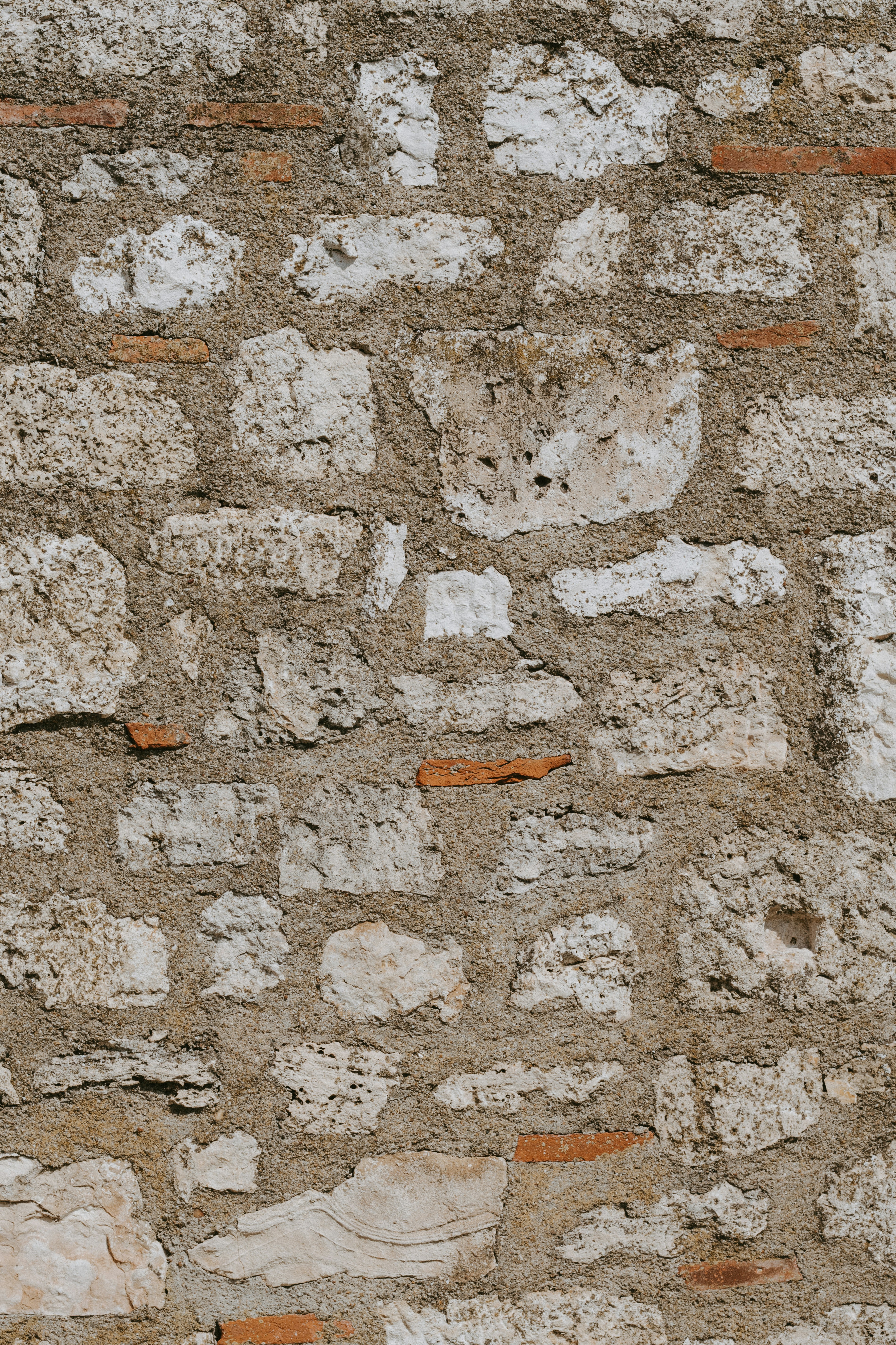 A rustic wall made of rough white stones and small red bricks.