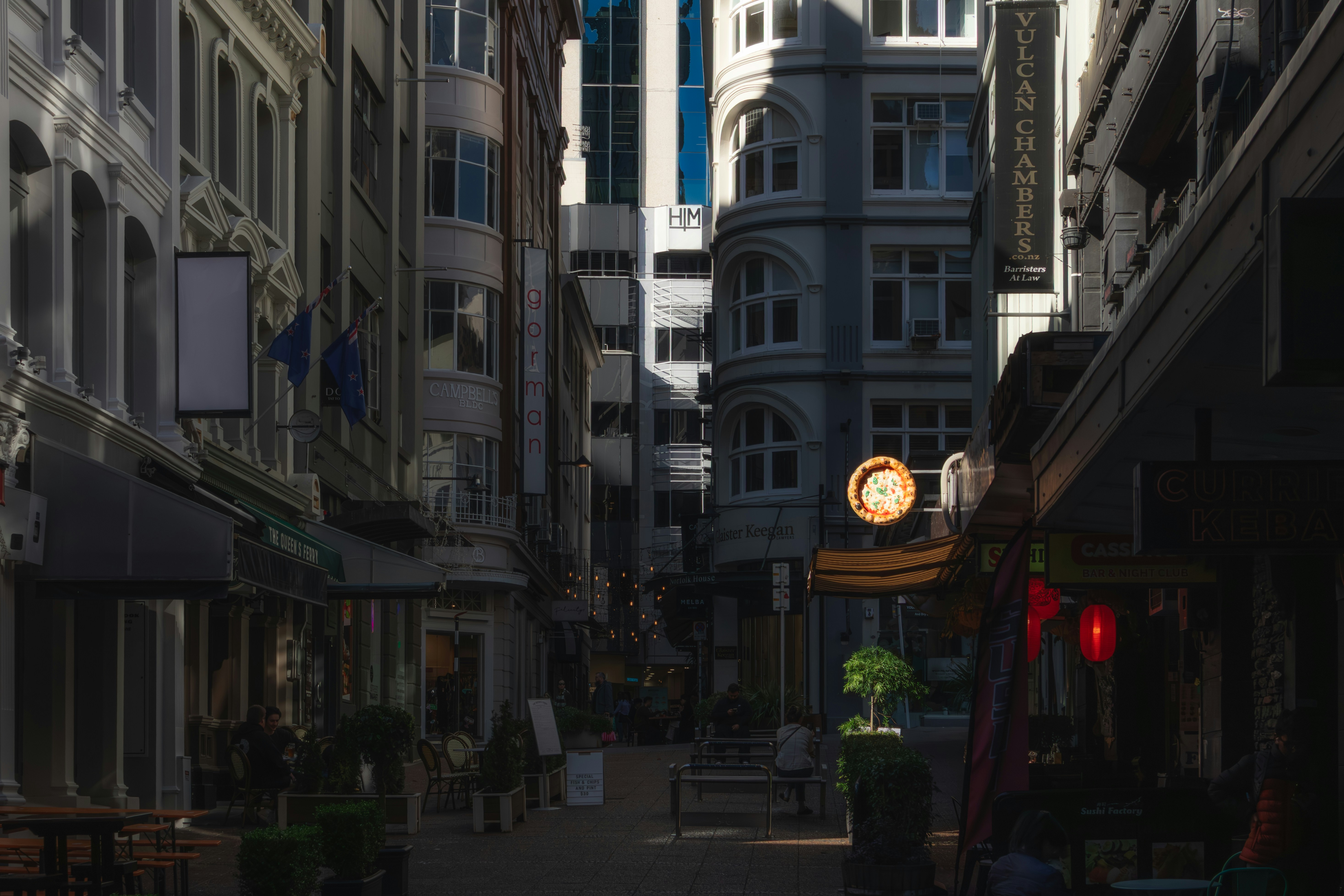 A narrow city street lined with historic buildings and illuminated shop signs