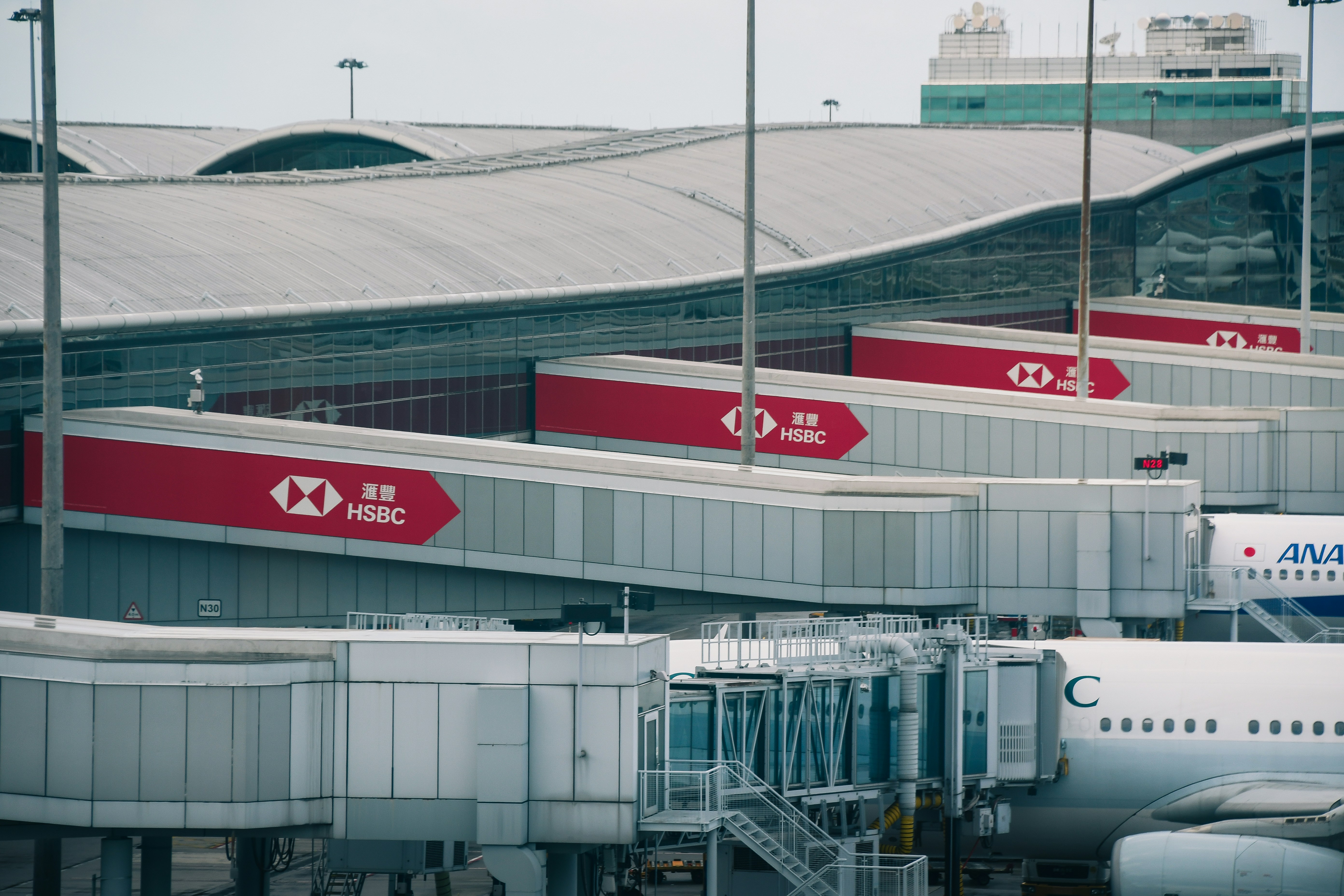Airport jet bridges with red HSBC branding at a terminal building
