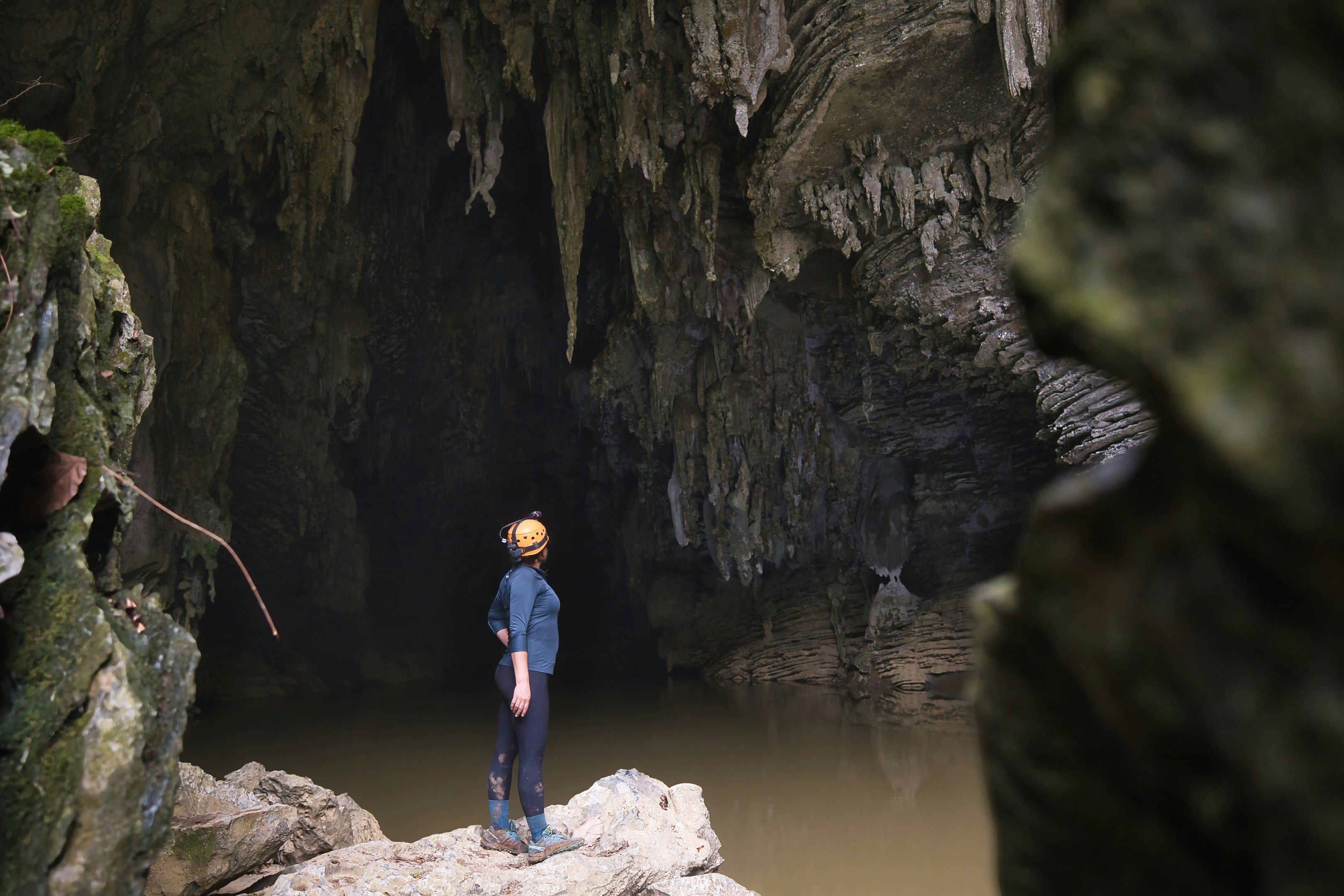 A person in a helmet and athletic gear exploring a dark limestone cave