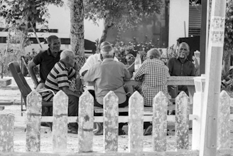 A group of older men sitting at a stone table outdoors