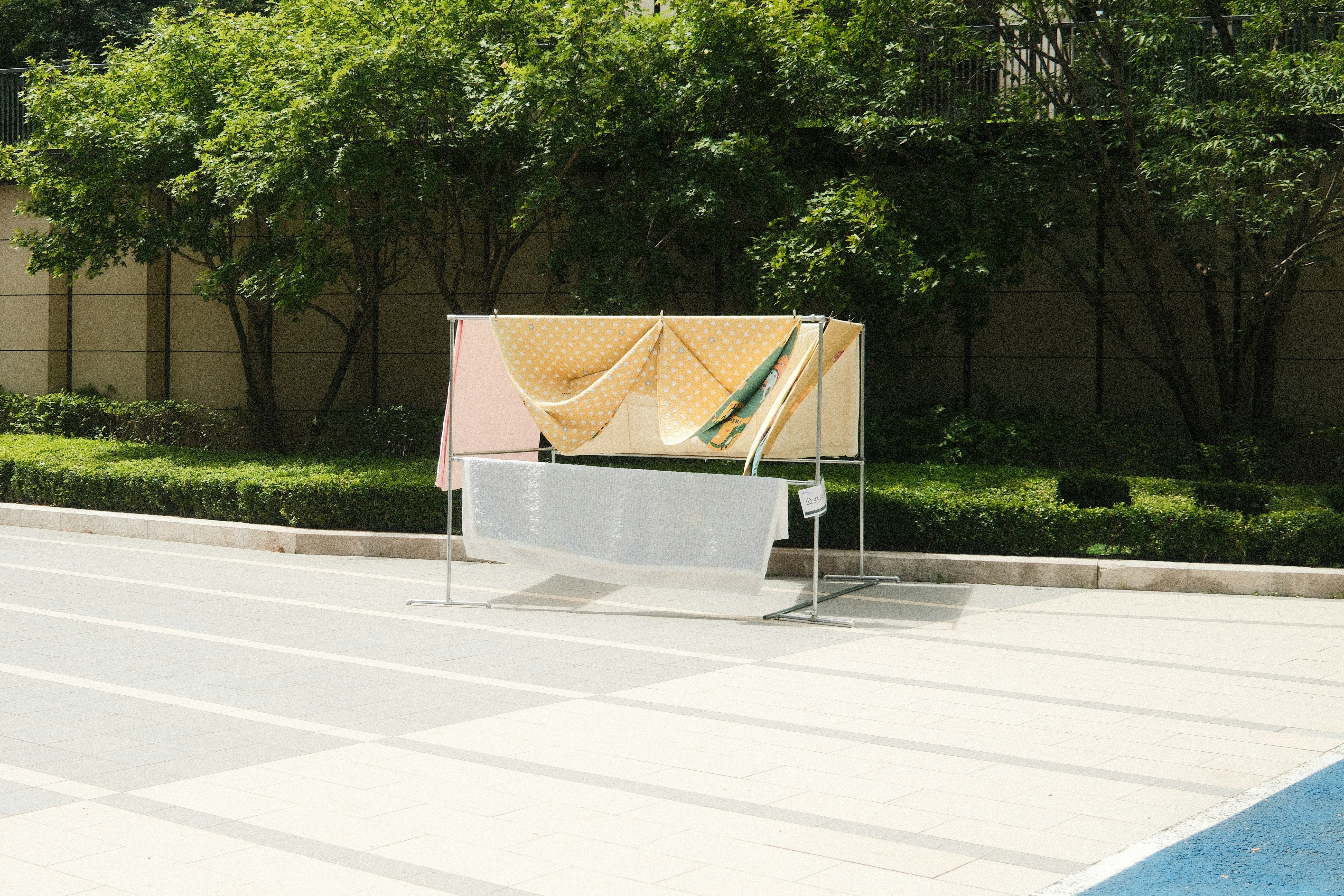 Laundry drying on a metal rack on a paved outdoor plaza