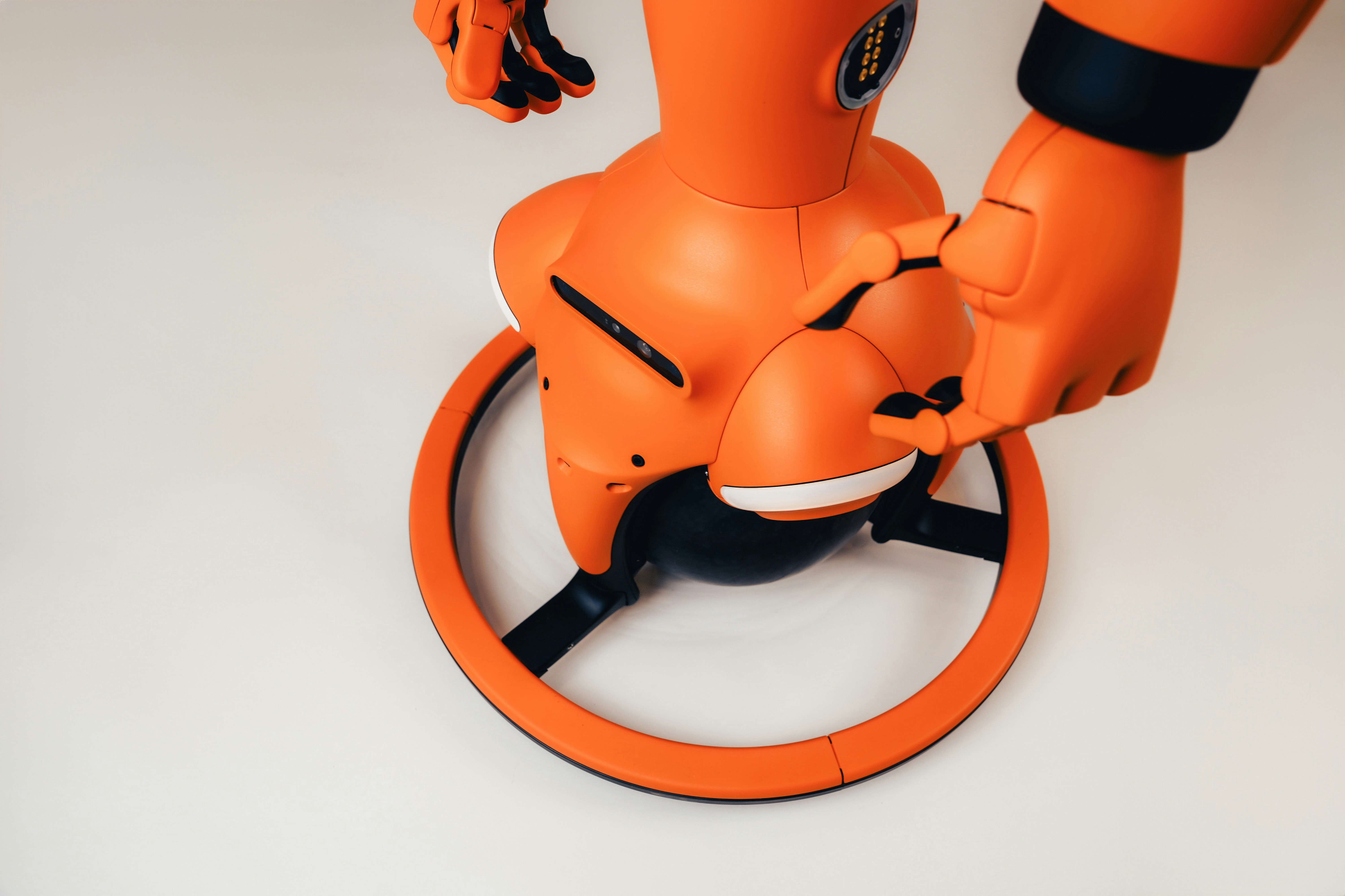 An orange robot with a circular base on a plain white surface