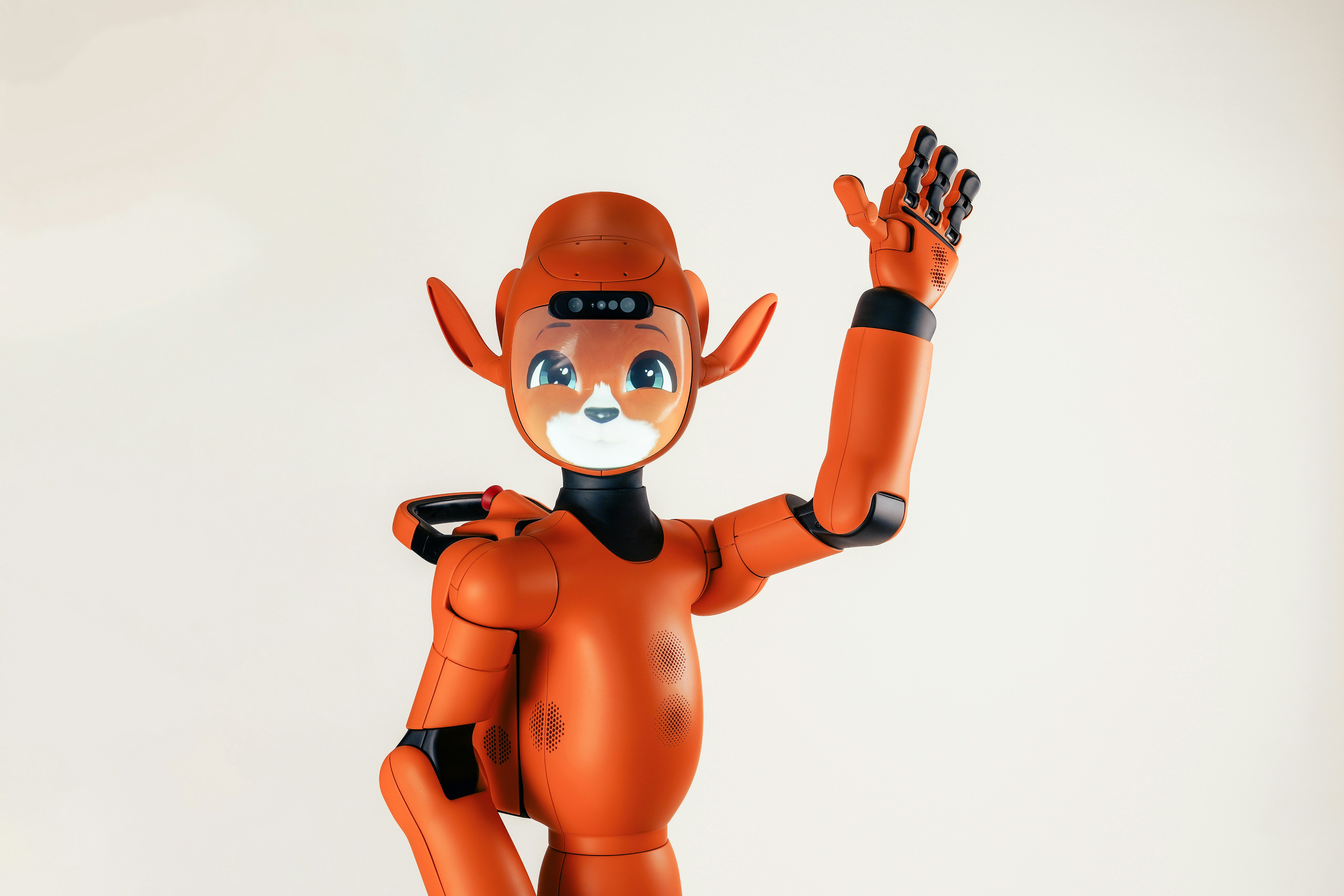 An orange humanoid robot with animal-like ears waving its hand against a white background