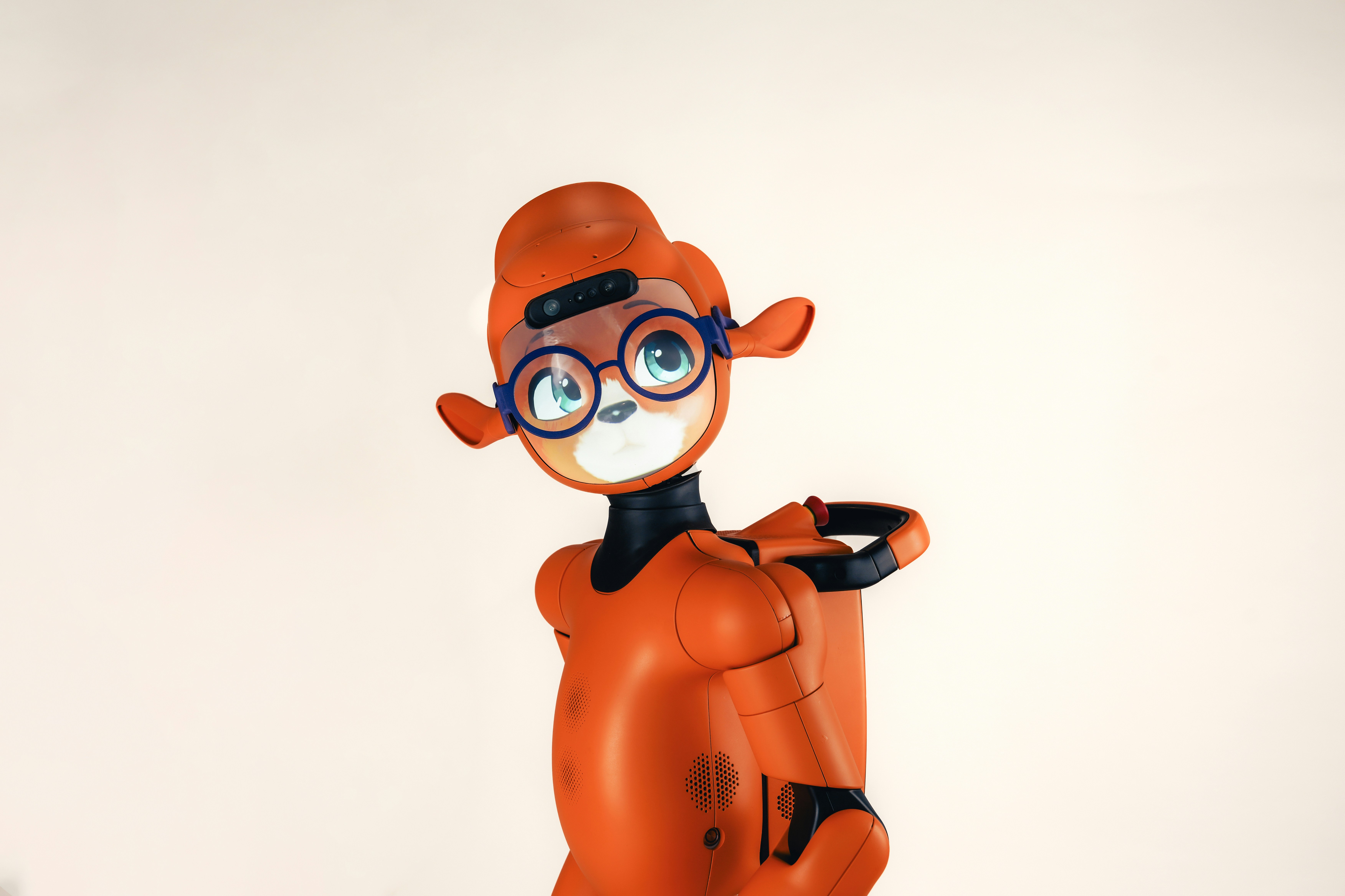 An orange robotic character with large blue glasses against a plain background