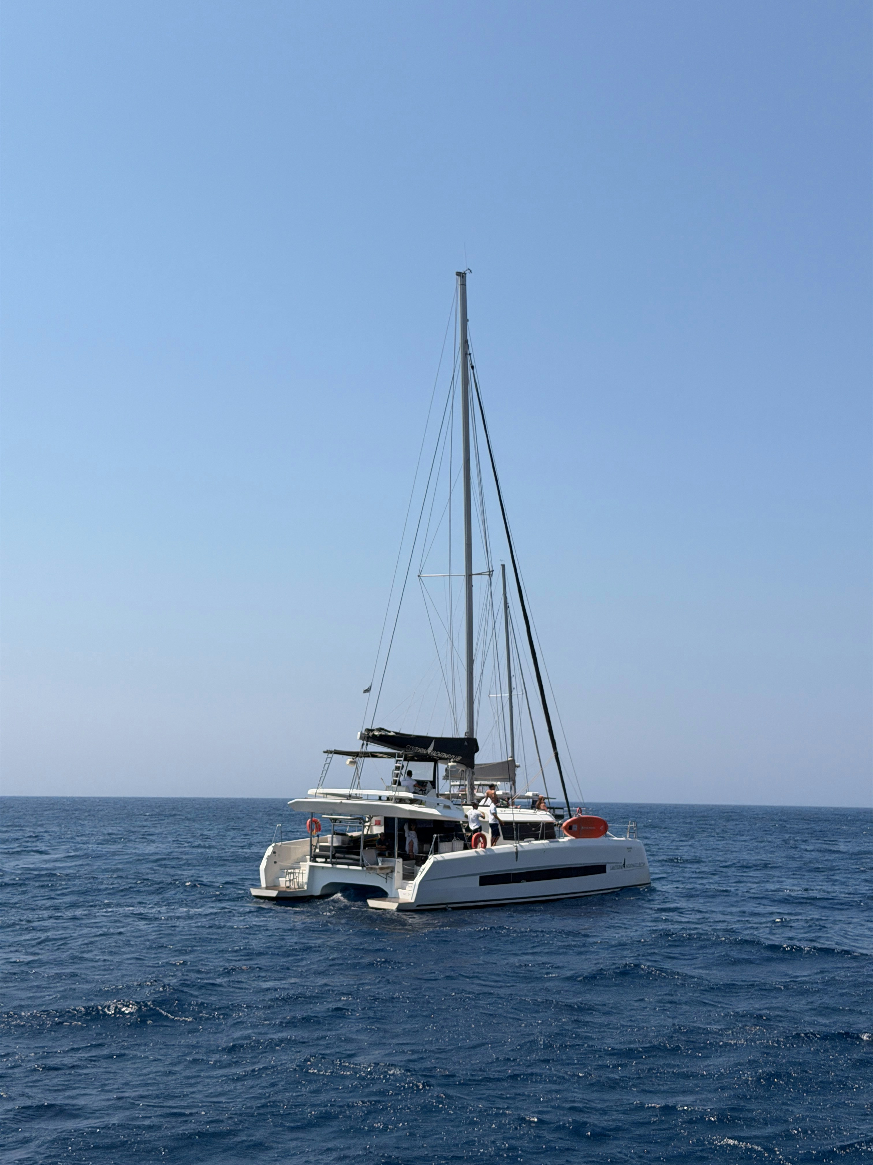 A white catamaran sailing on the deep blue sea under a clear sky
