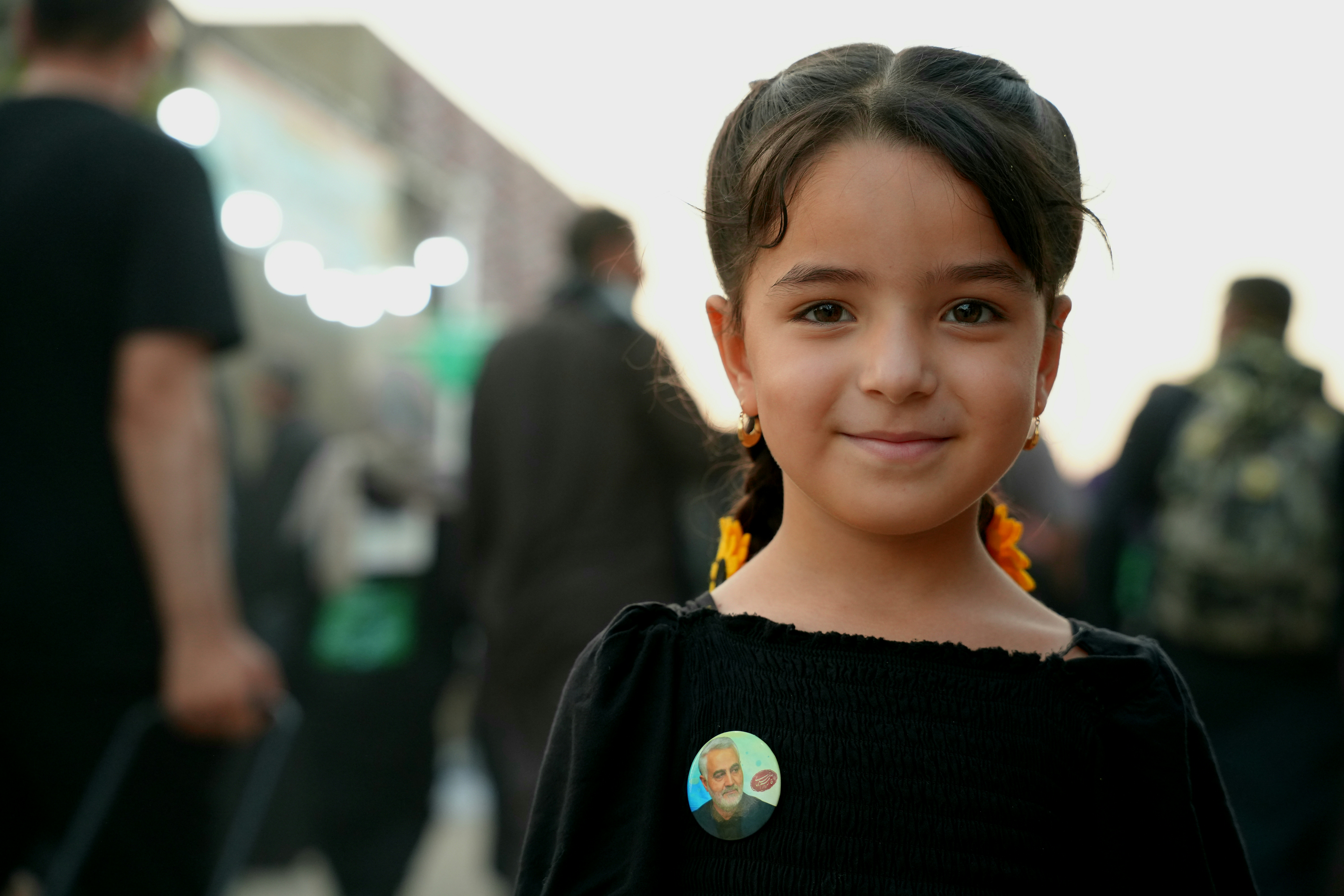 A young girl in a black shirt with a small portrait pin