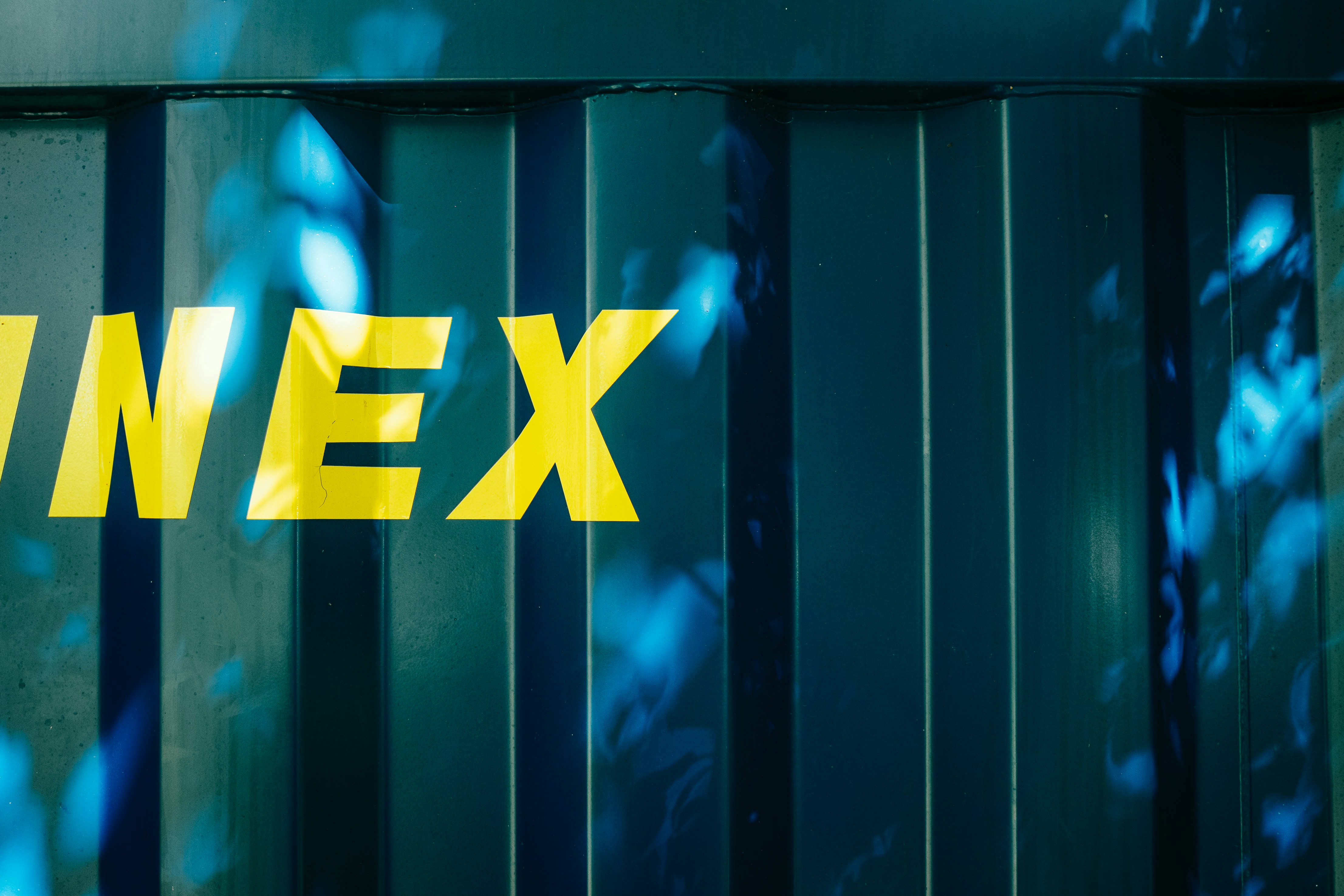 Letras amarelas sobre uma superfície de metal ondulado azul-escuro com padrões de luz salpicados