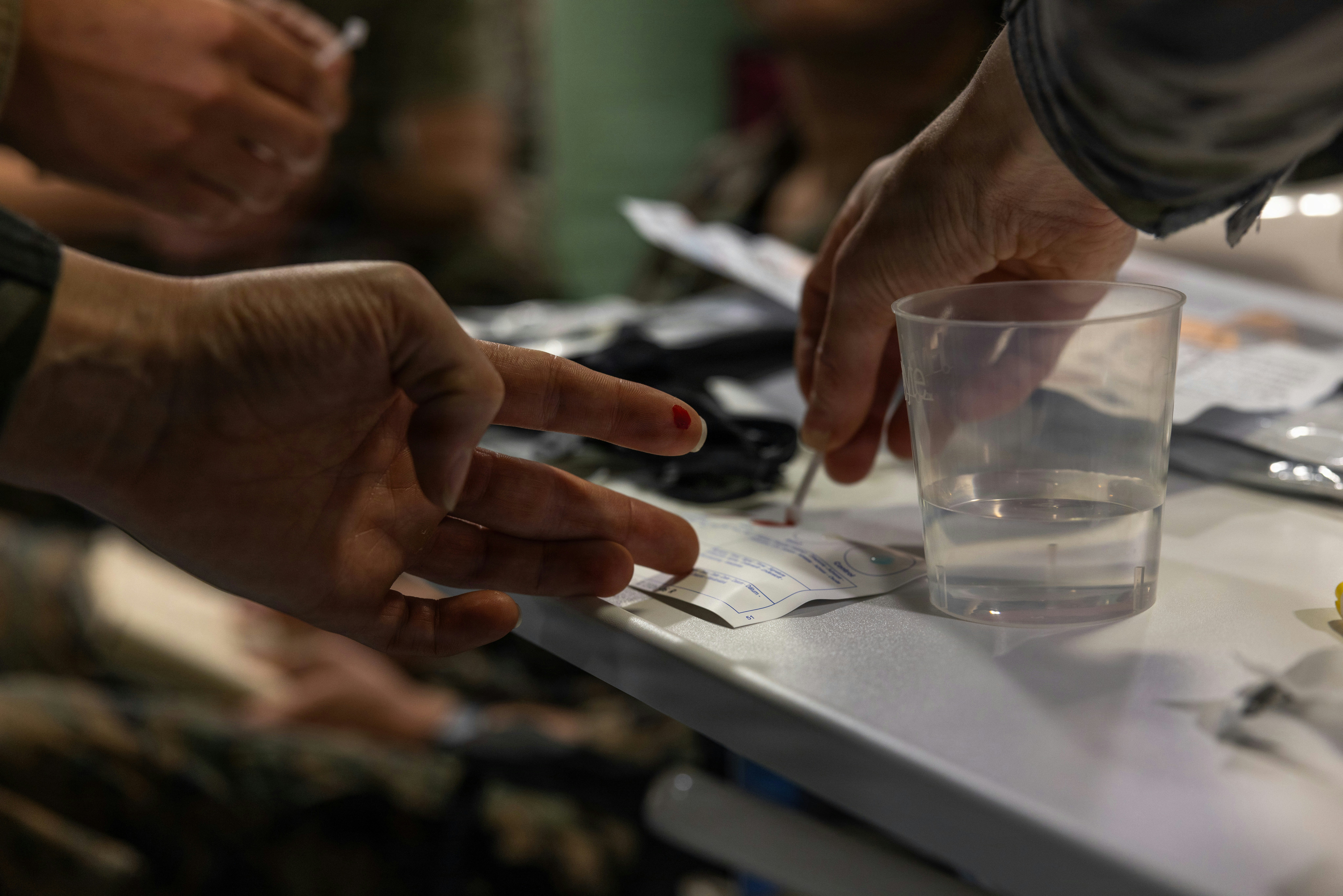 A person applying a drop of blood from their finger onto a test card.