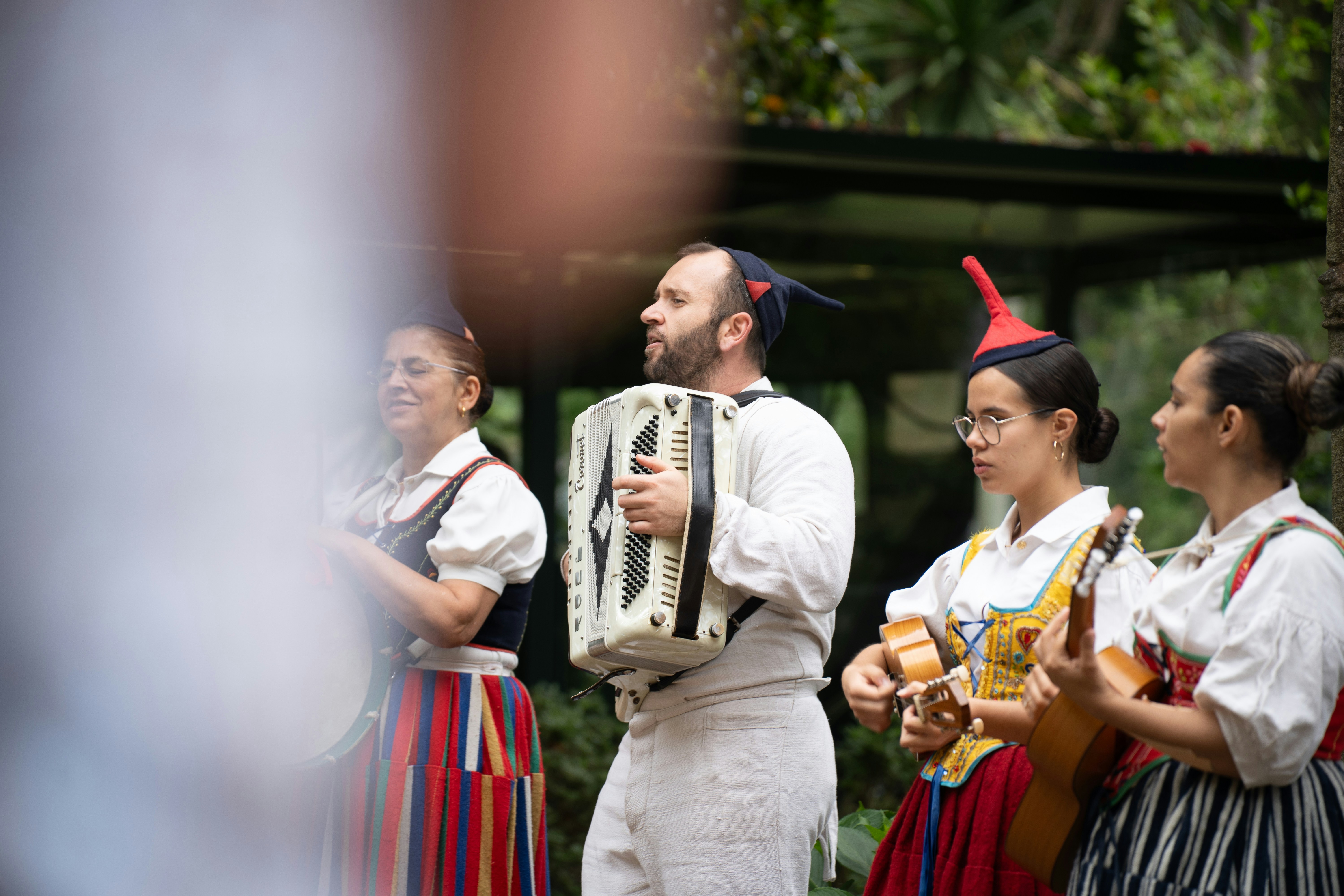 A group of people in traditional folk costumes playing instruments in a garden.