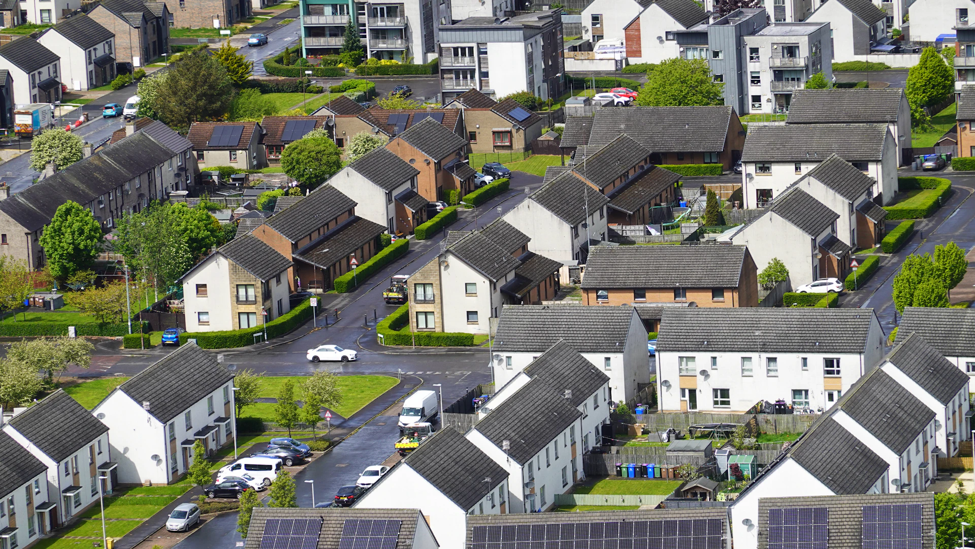 Aerial view of a suburban neighborhood with houses, paved streets, and green lawns