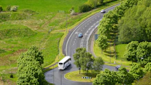 White coach bus driving along a curved rural road