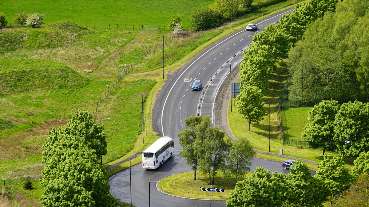 White coach bus driving along a curved rural road