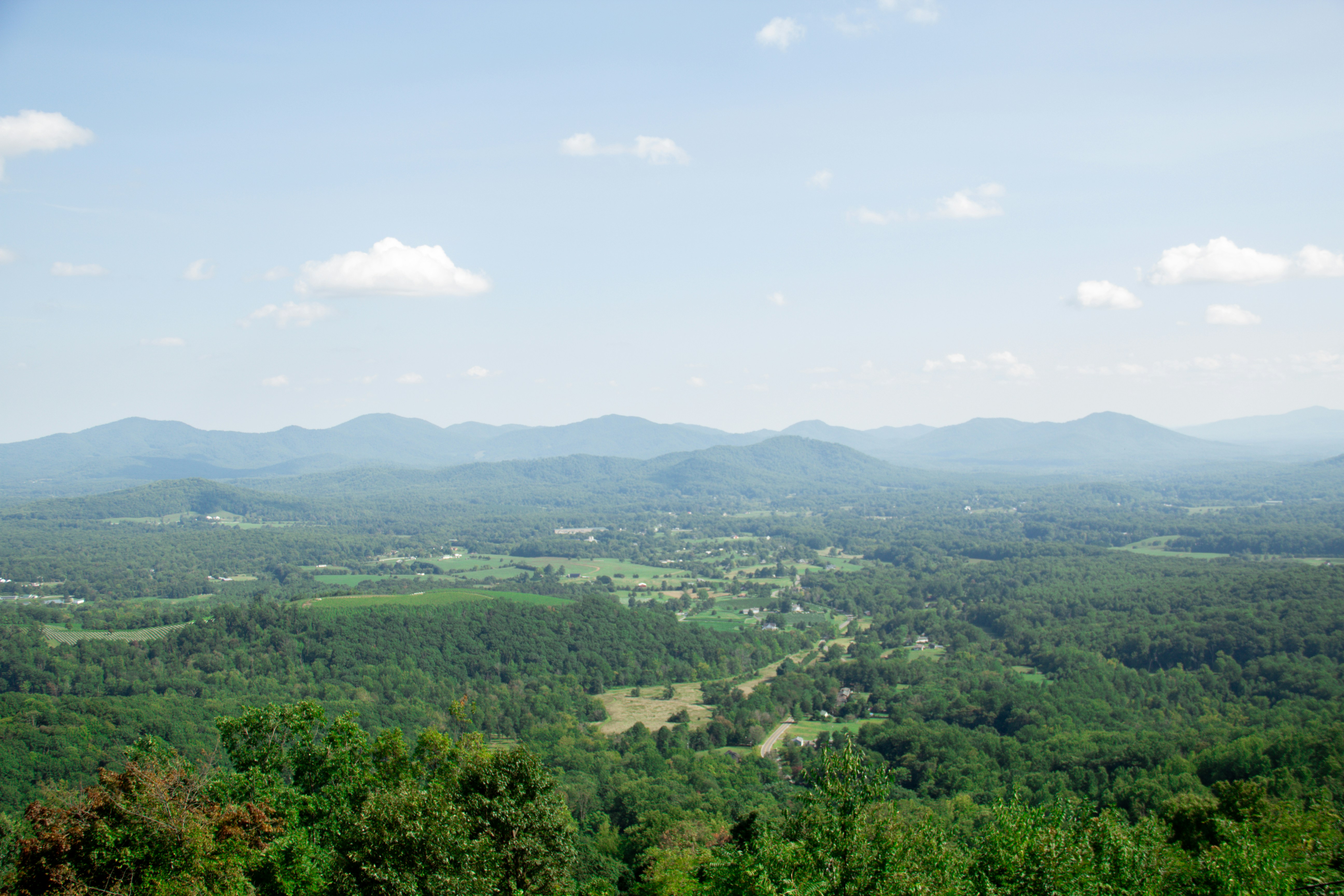 A wide view of a green valley with rolling hills under a blue sky