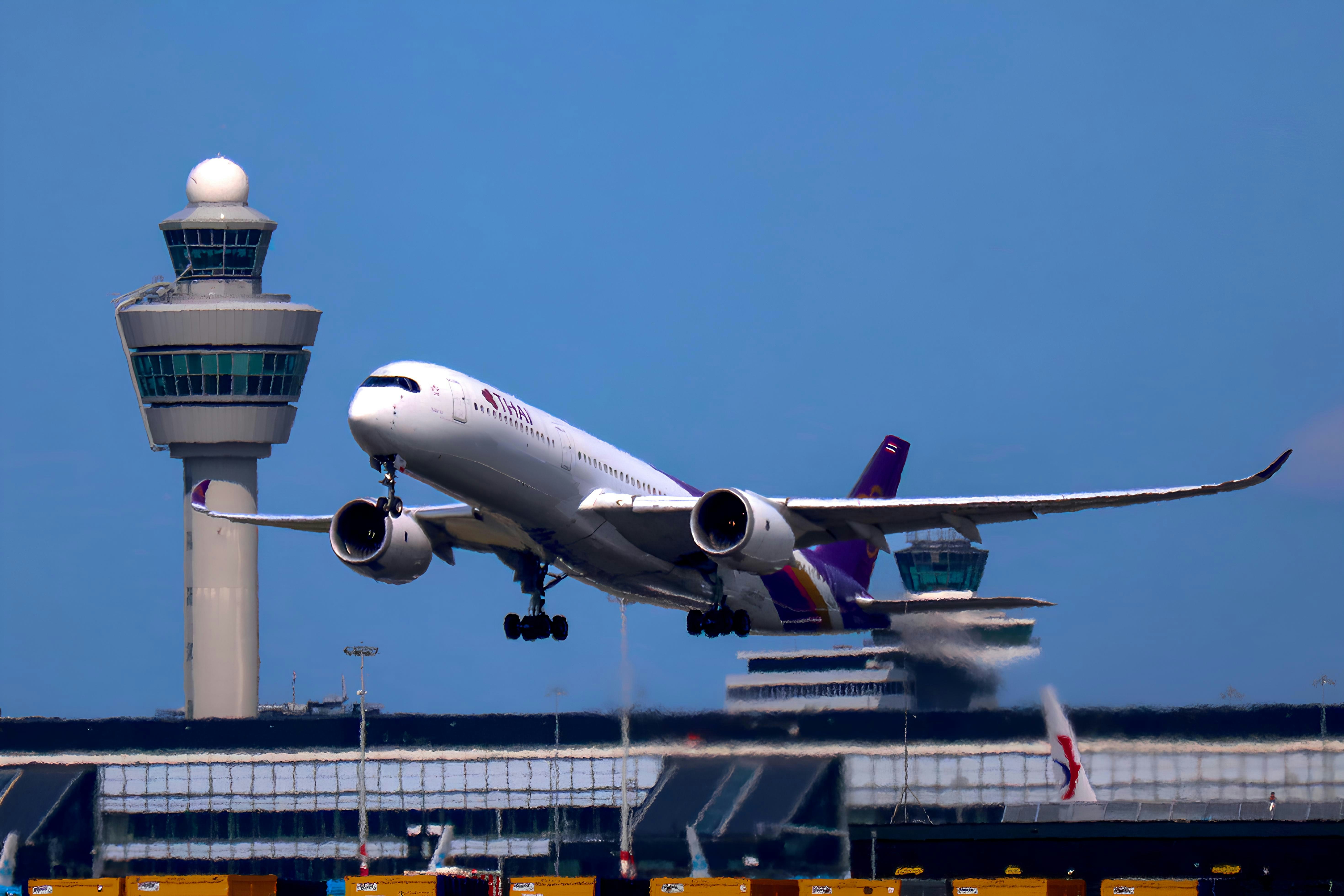 A Thai Airways passenger jet taking off past an airport control tower
