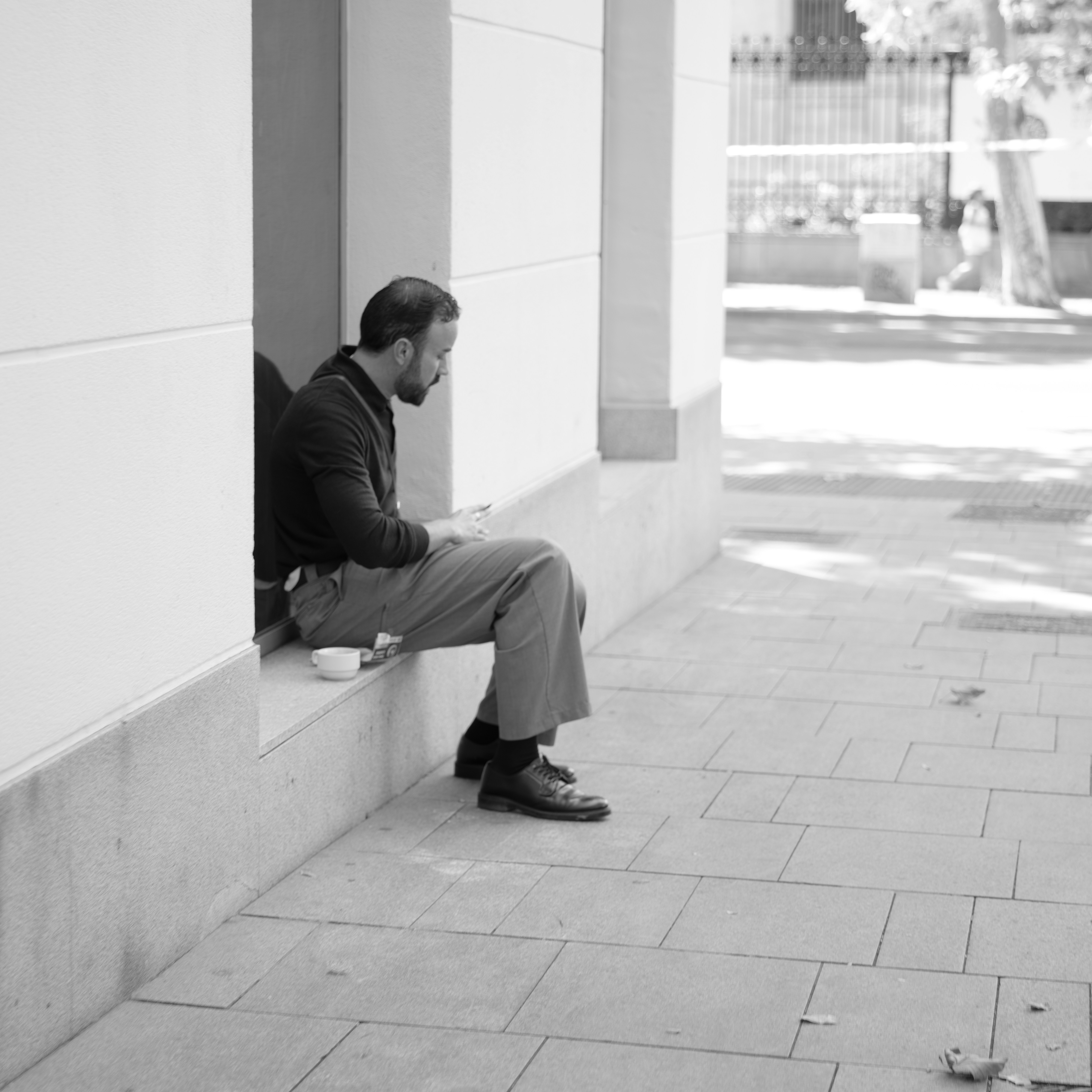 expectancy: A man in a dark shirt and trousers using a phone on a ledge