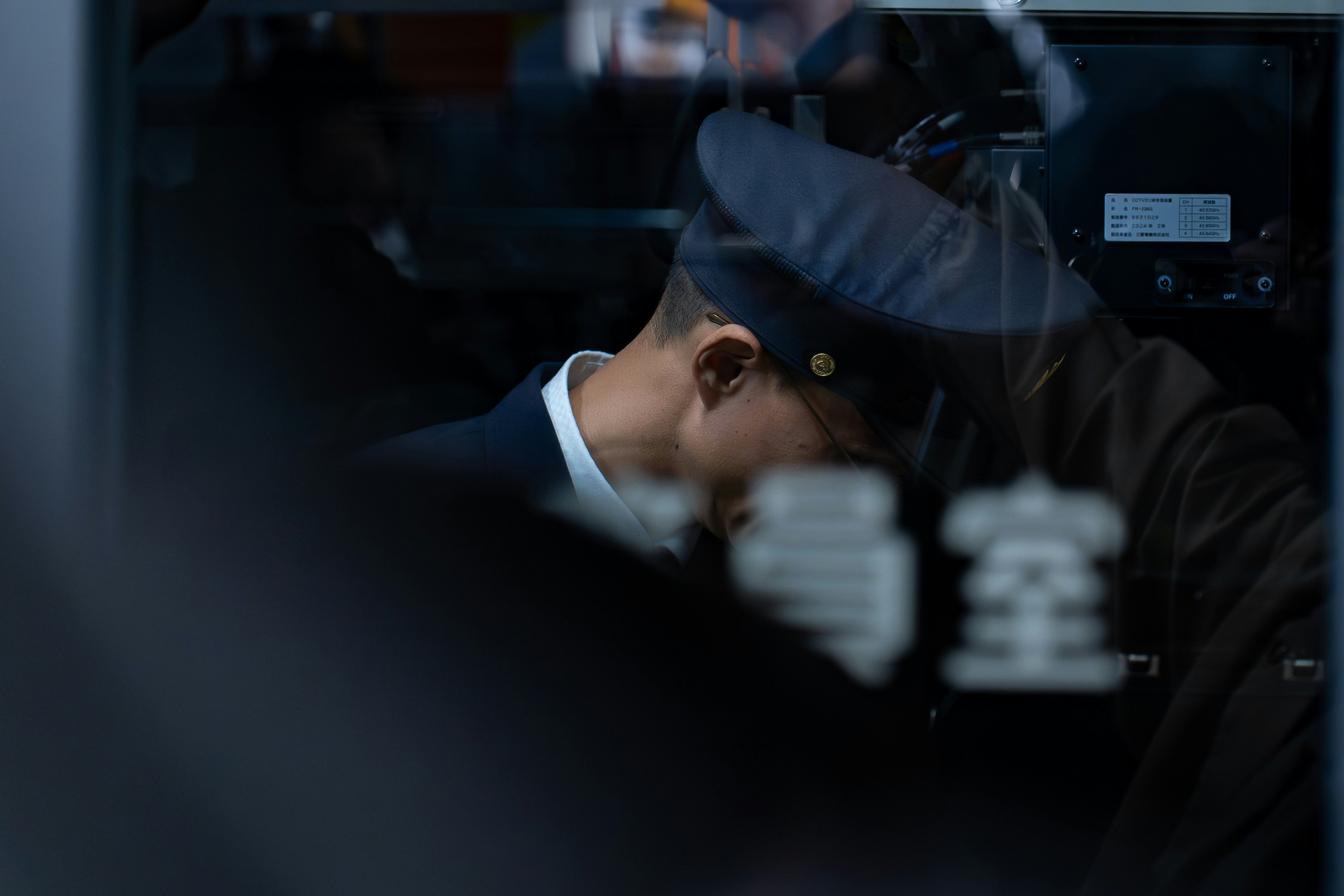Un chef de train en uniforme sombre et casquette à l’intérieur d’une cabine de train.