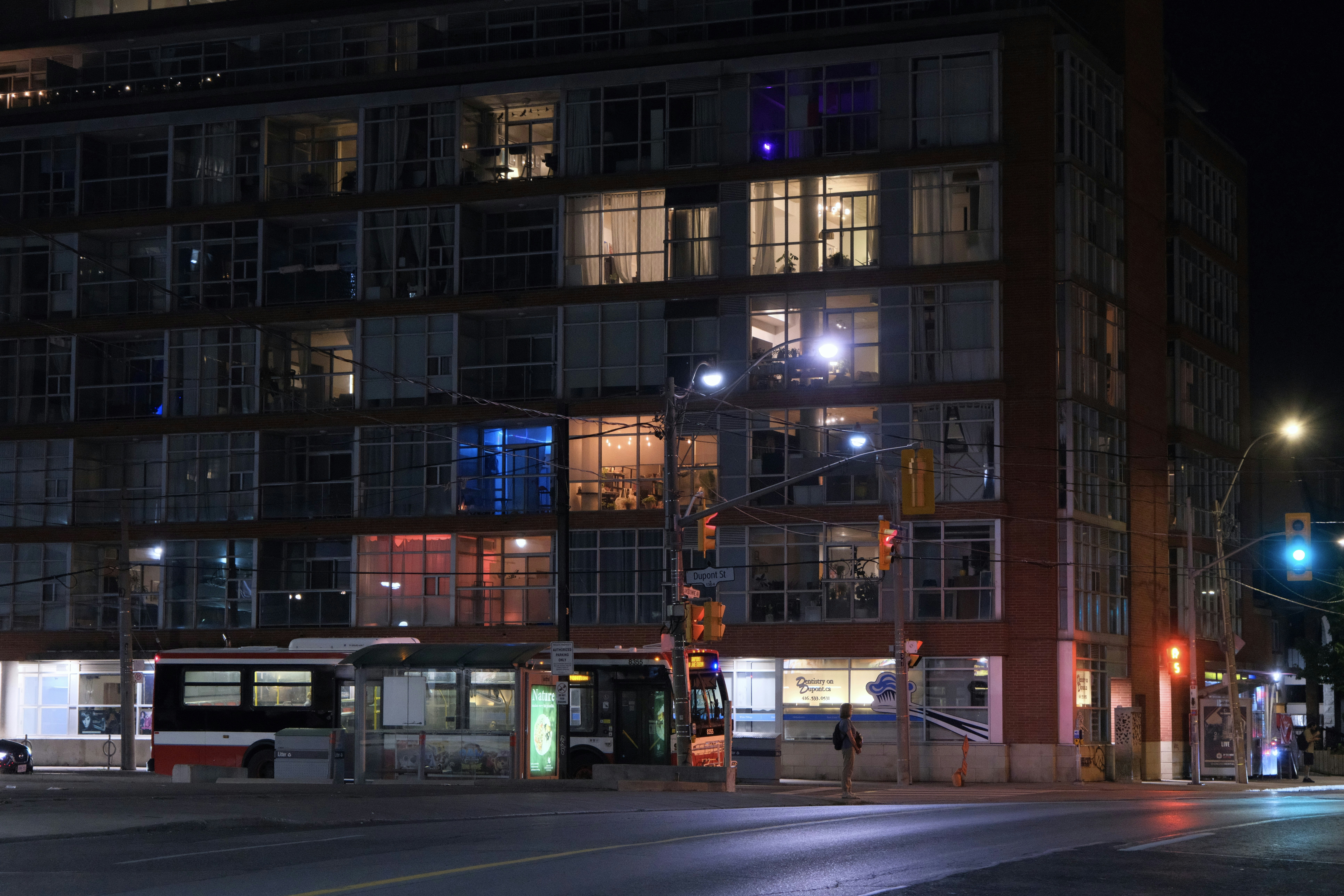 City street at night with a bus pulled up beneath apartment blocks