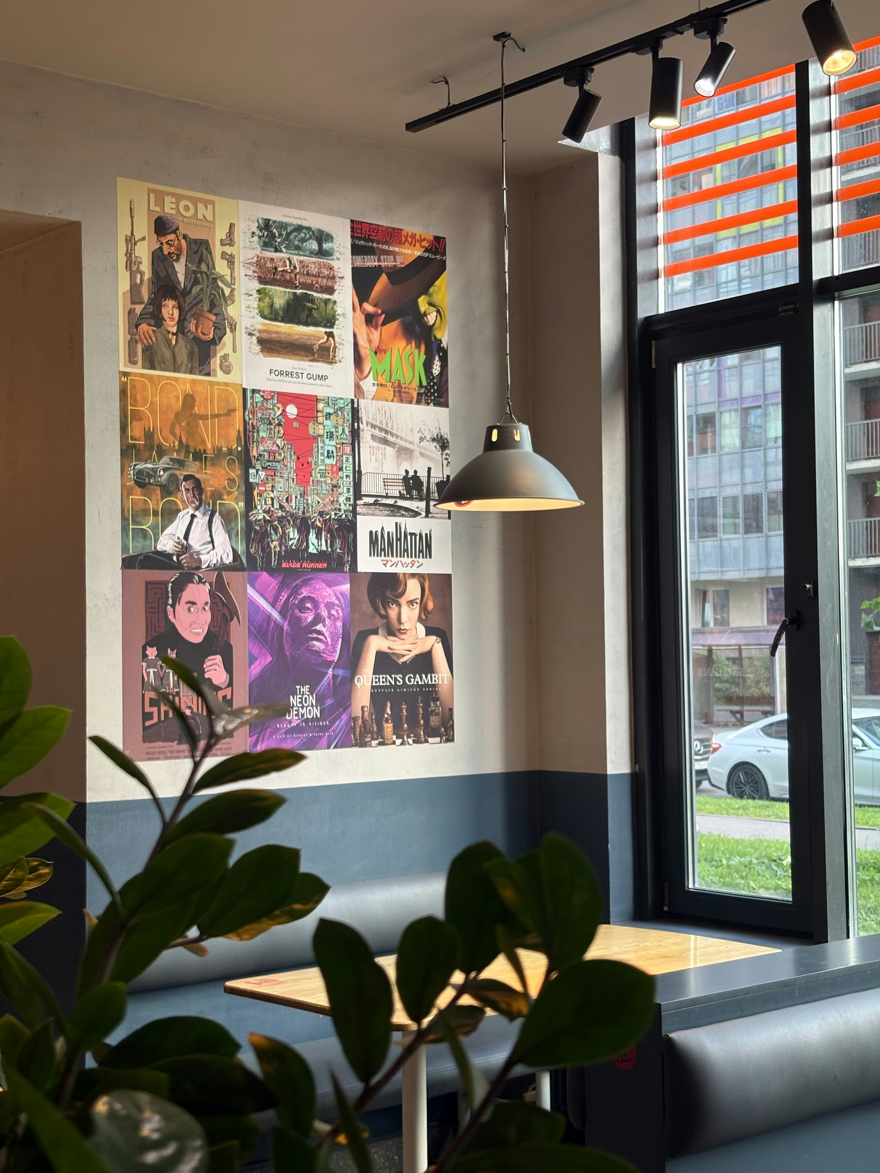 A wall decorated with a grid of movie posters above a booth in a cafe