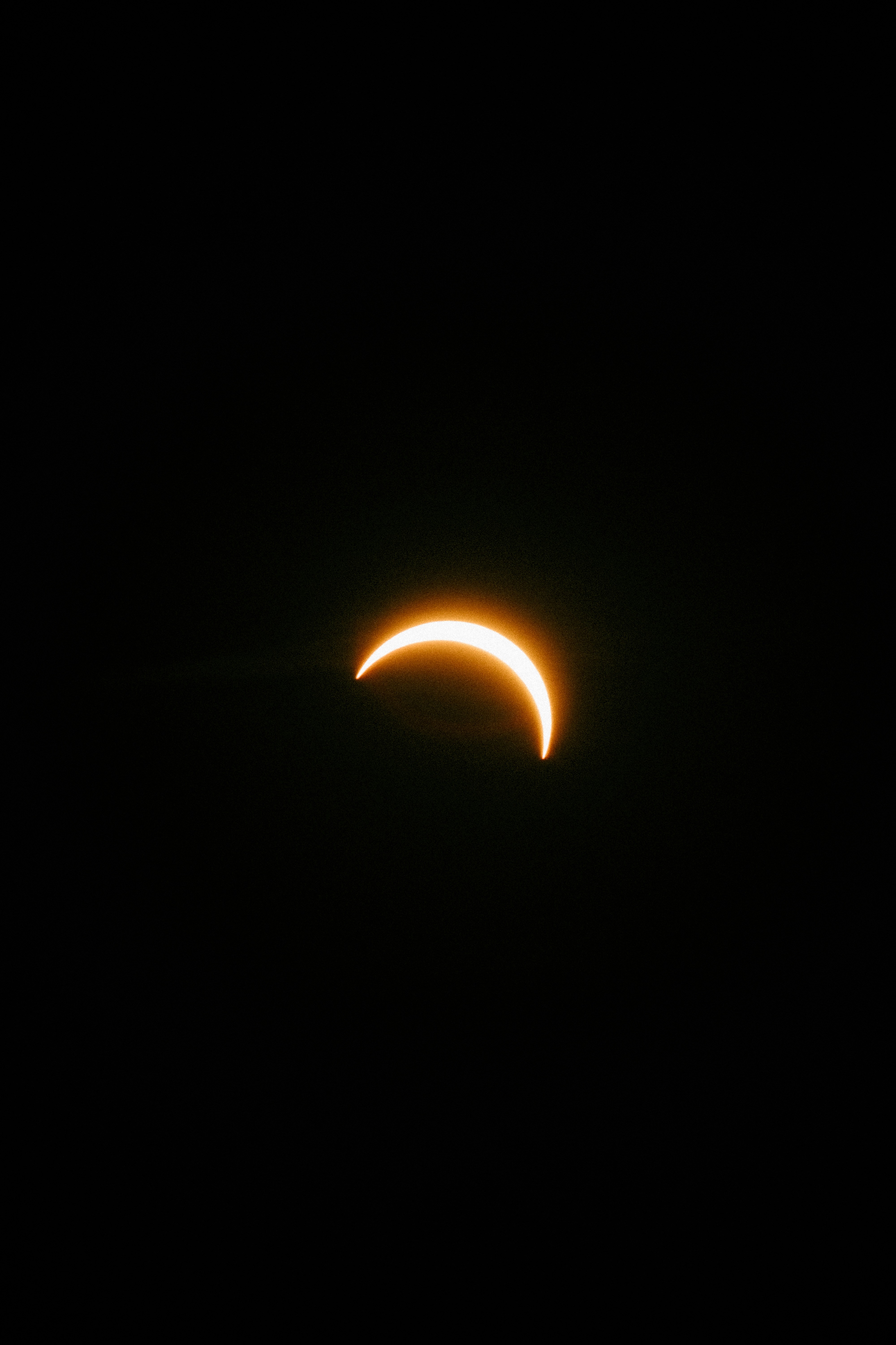 A bright crescent sun during a partial solar eclipse against a black sky.
