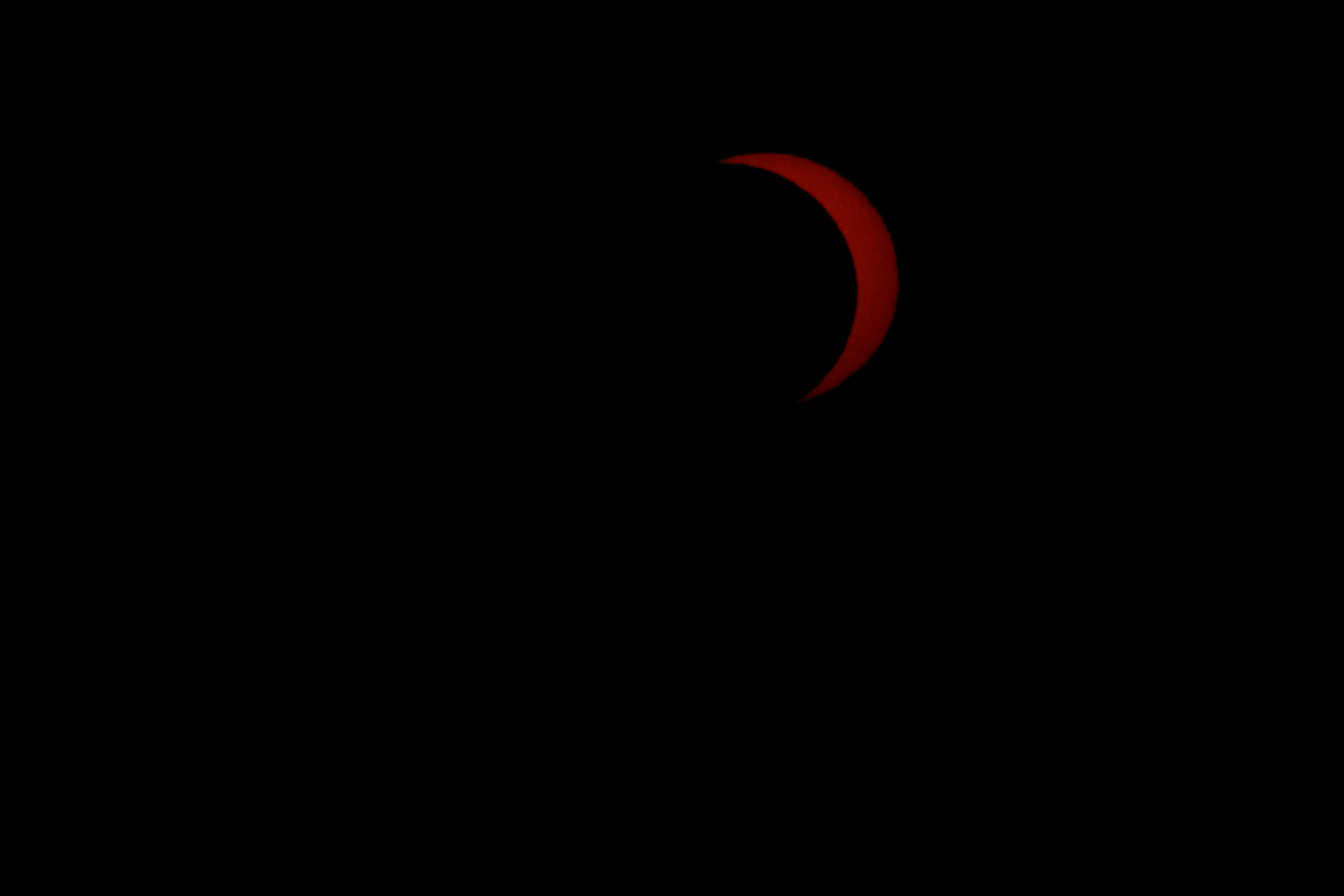 A thin red crescent of the sun during a solar eclipse