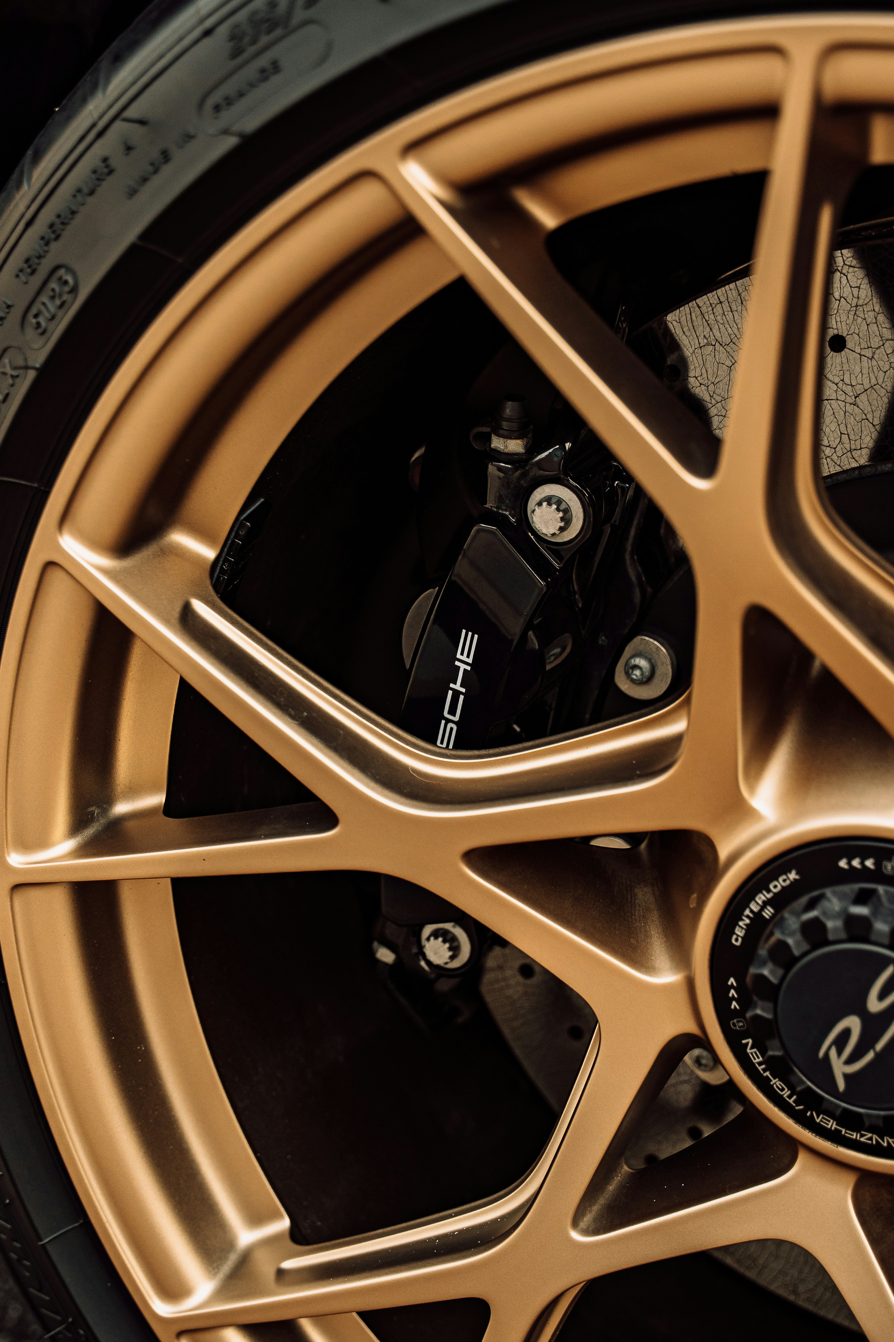 A gold alloy wheel with a black brake caliper on a sports car.