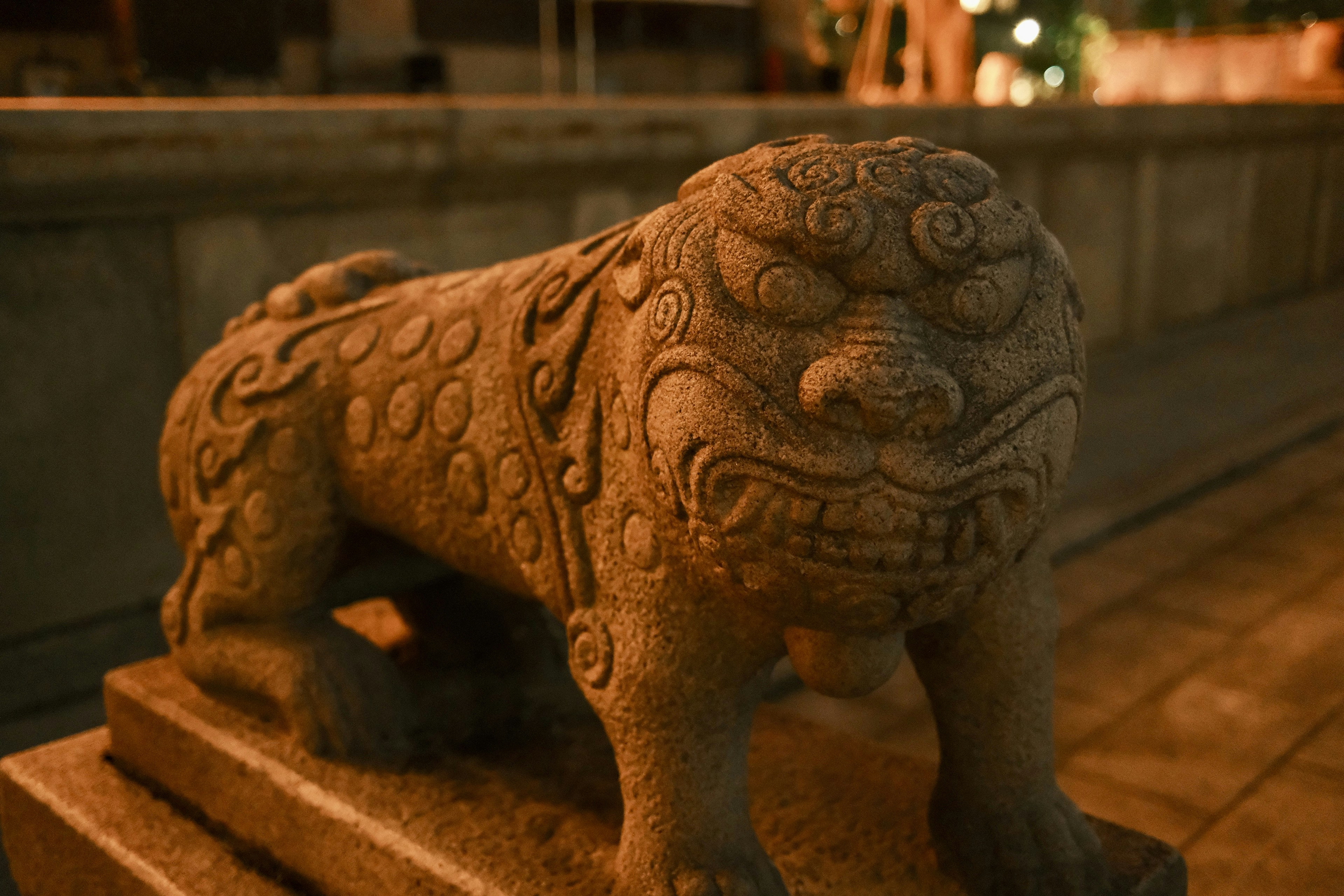 A stone guardian lion statue illuminated by warm light at night