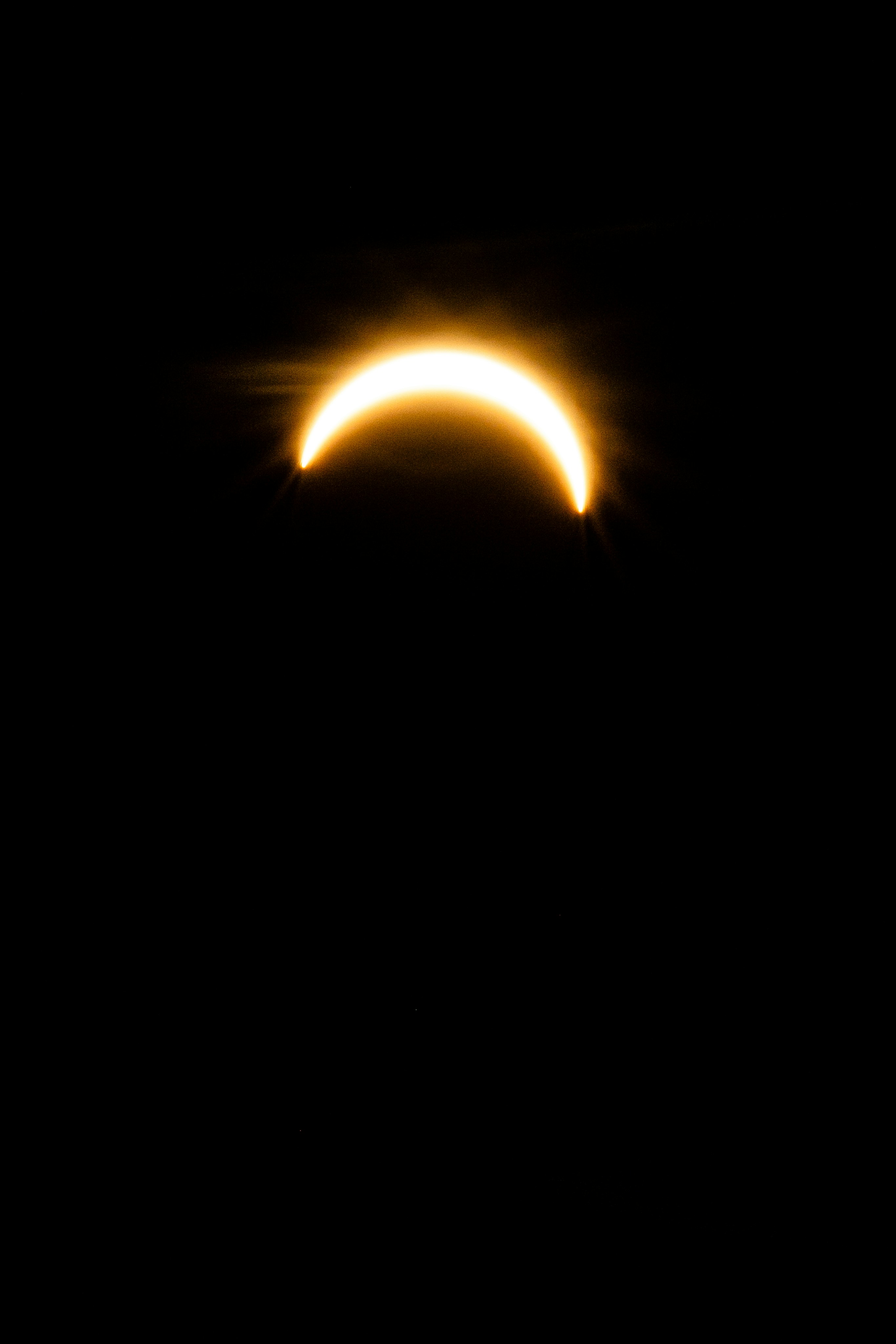 A bright crescent of light glowing against a deep black sky.