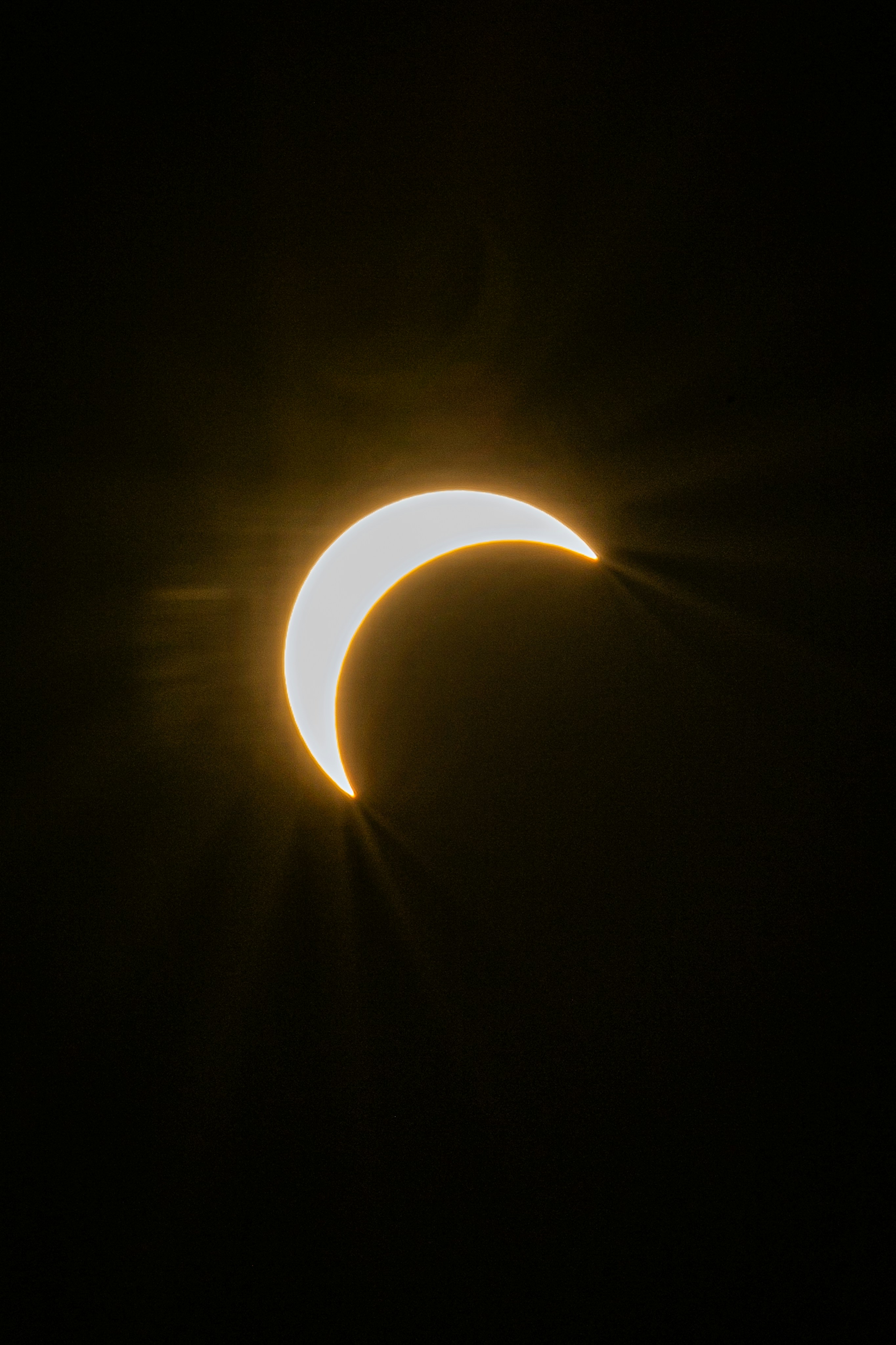 A bright crescent sun glowing against a dark black sky.
