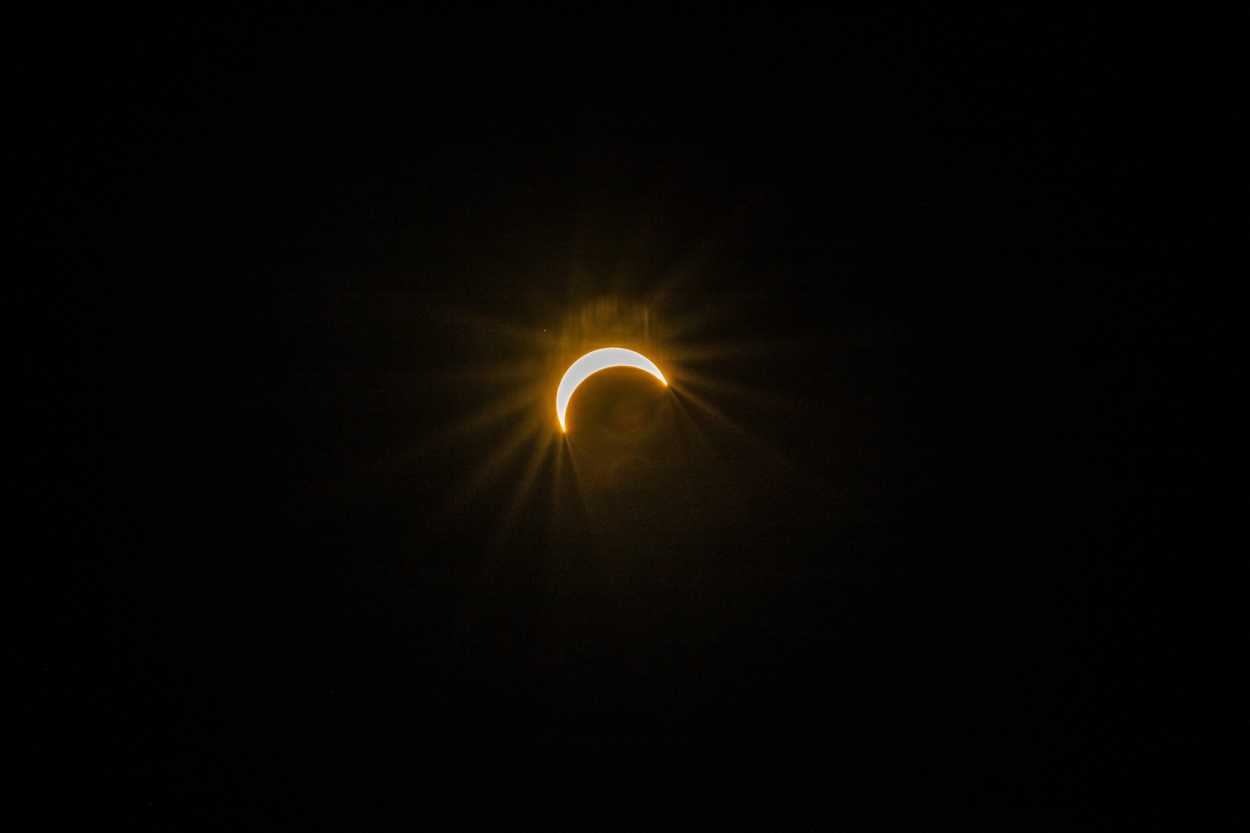 A crescent sun partially eclipsed by the moon against a dark sky.