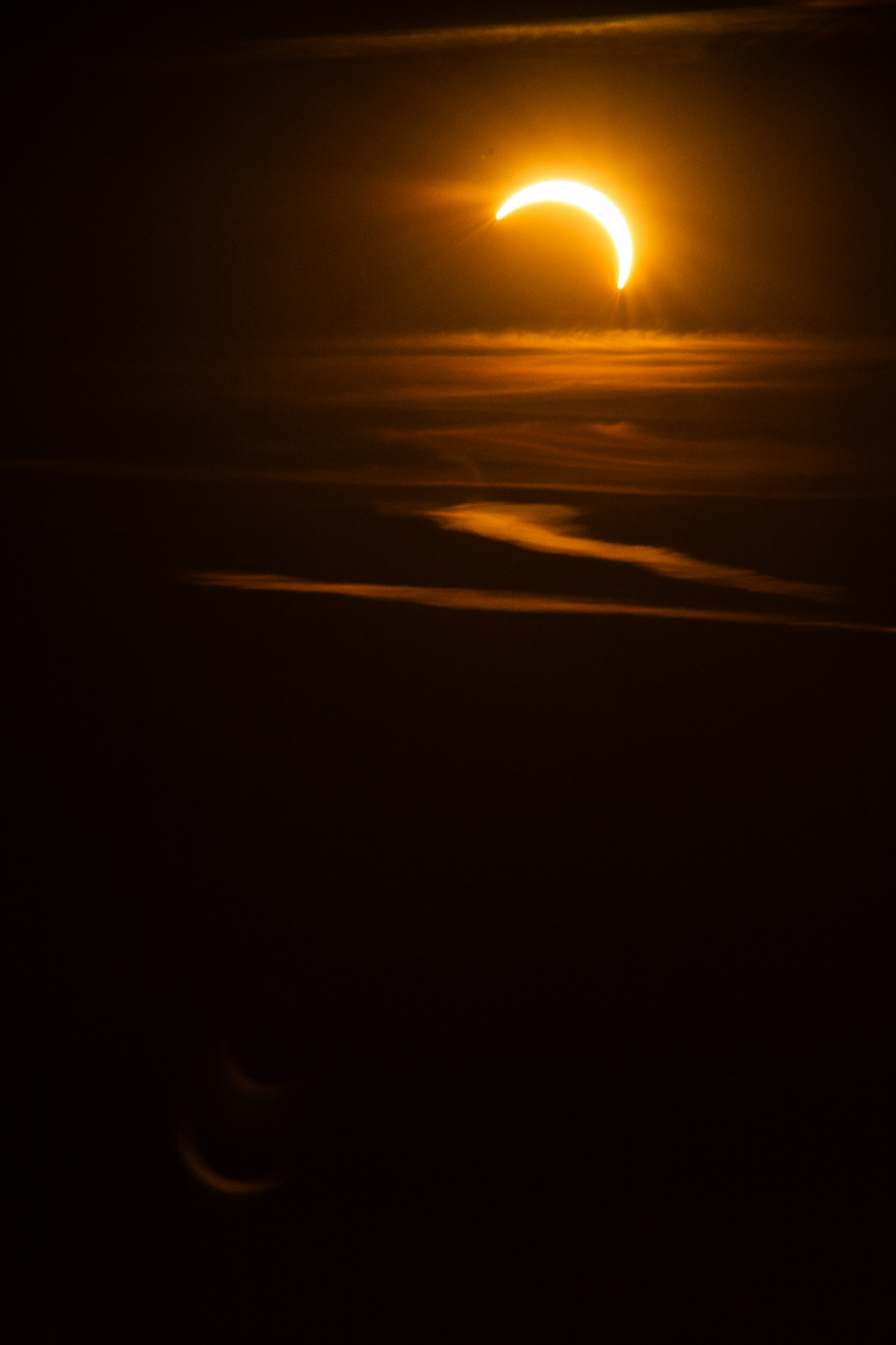 A crescent sun partially obscured by dark clouds in a night sky.