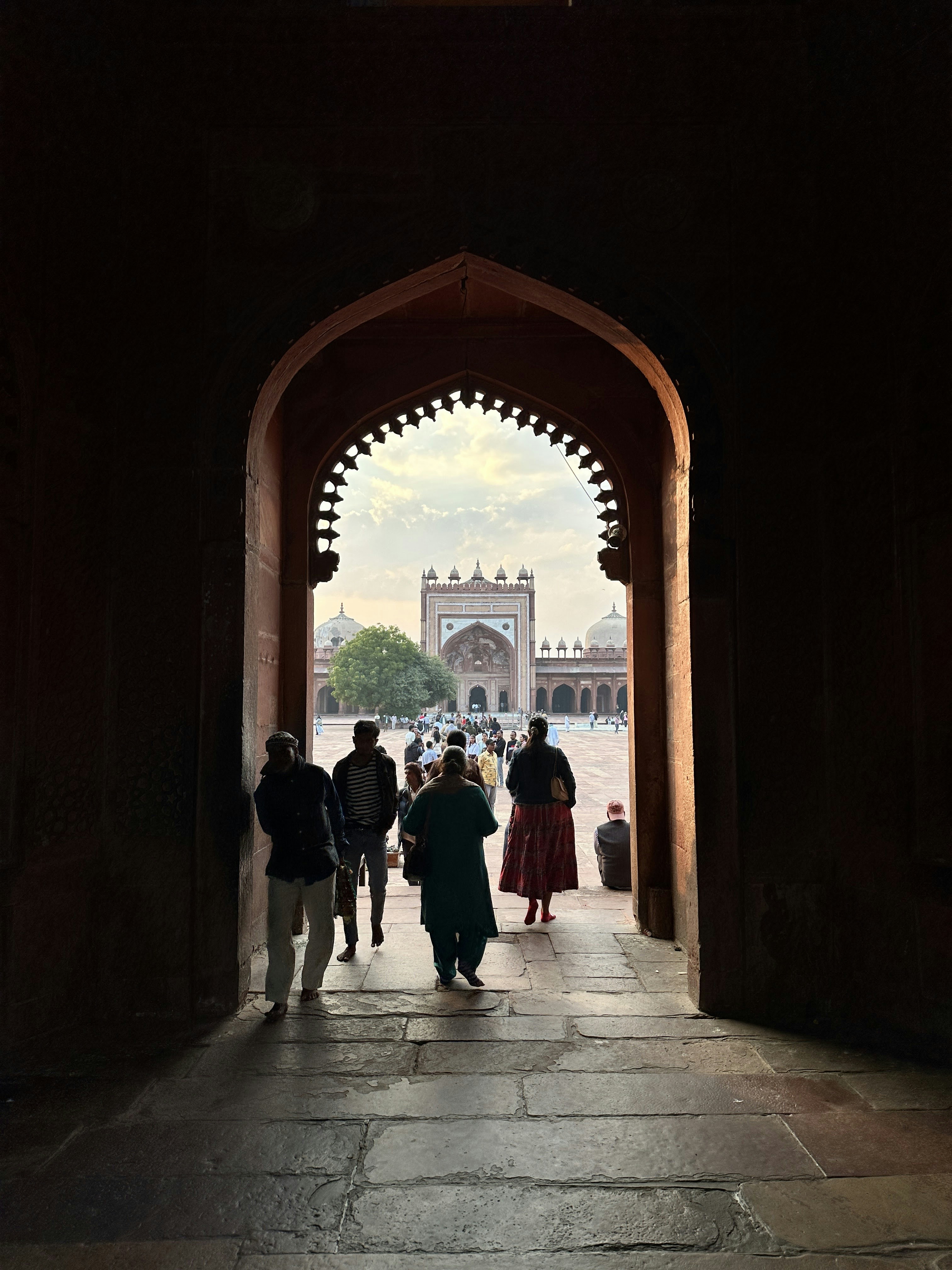People walking through a stone archway toward the Buland Darwaza in Fatehpur Sikri.