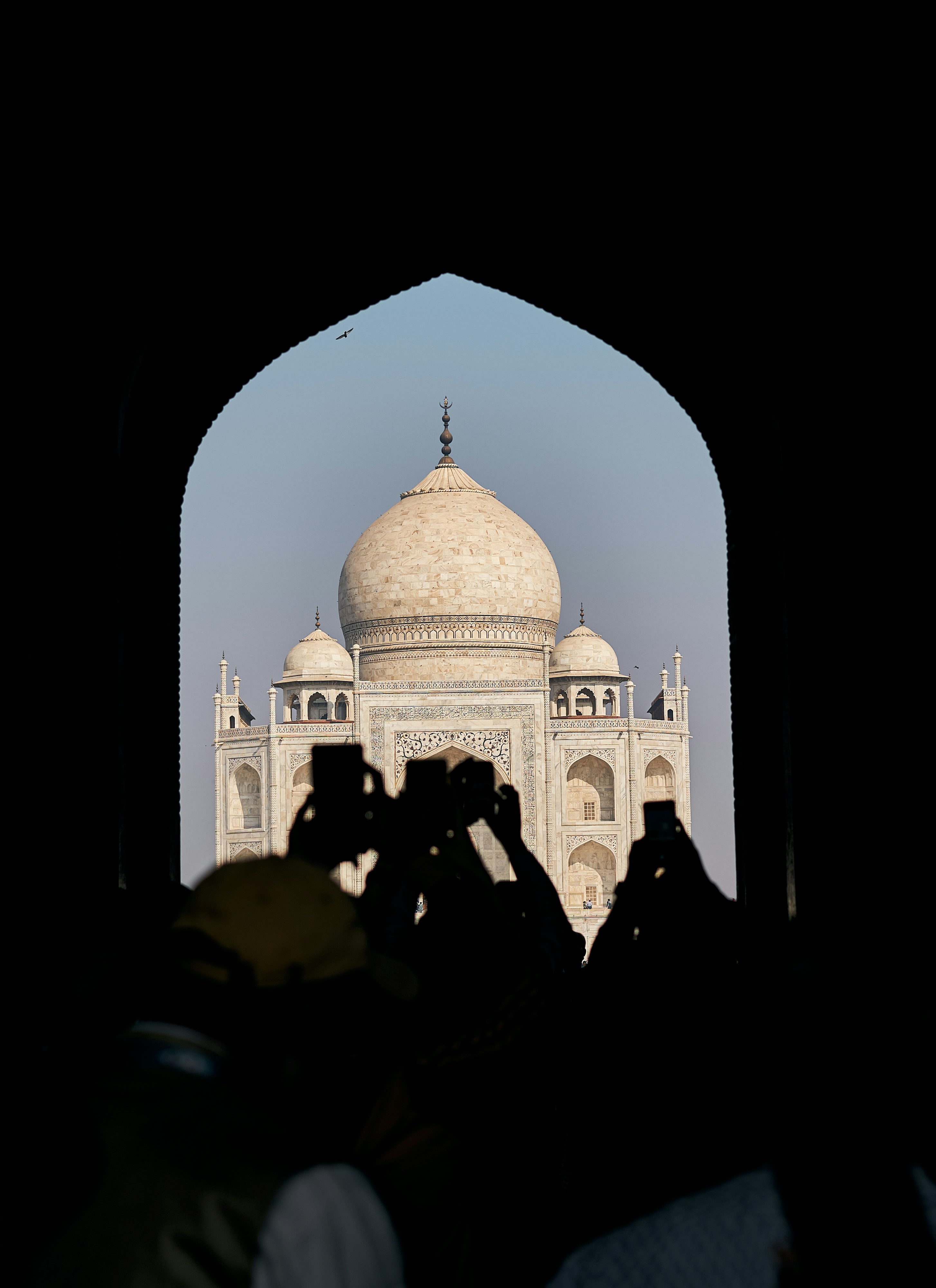 Silhouettes of people holding up phones to photograph the Taj Mahal in Agra.