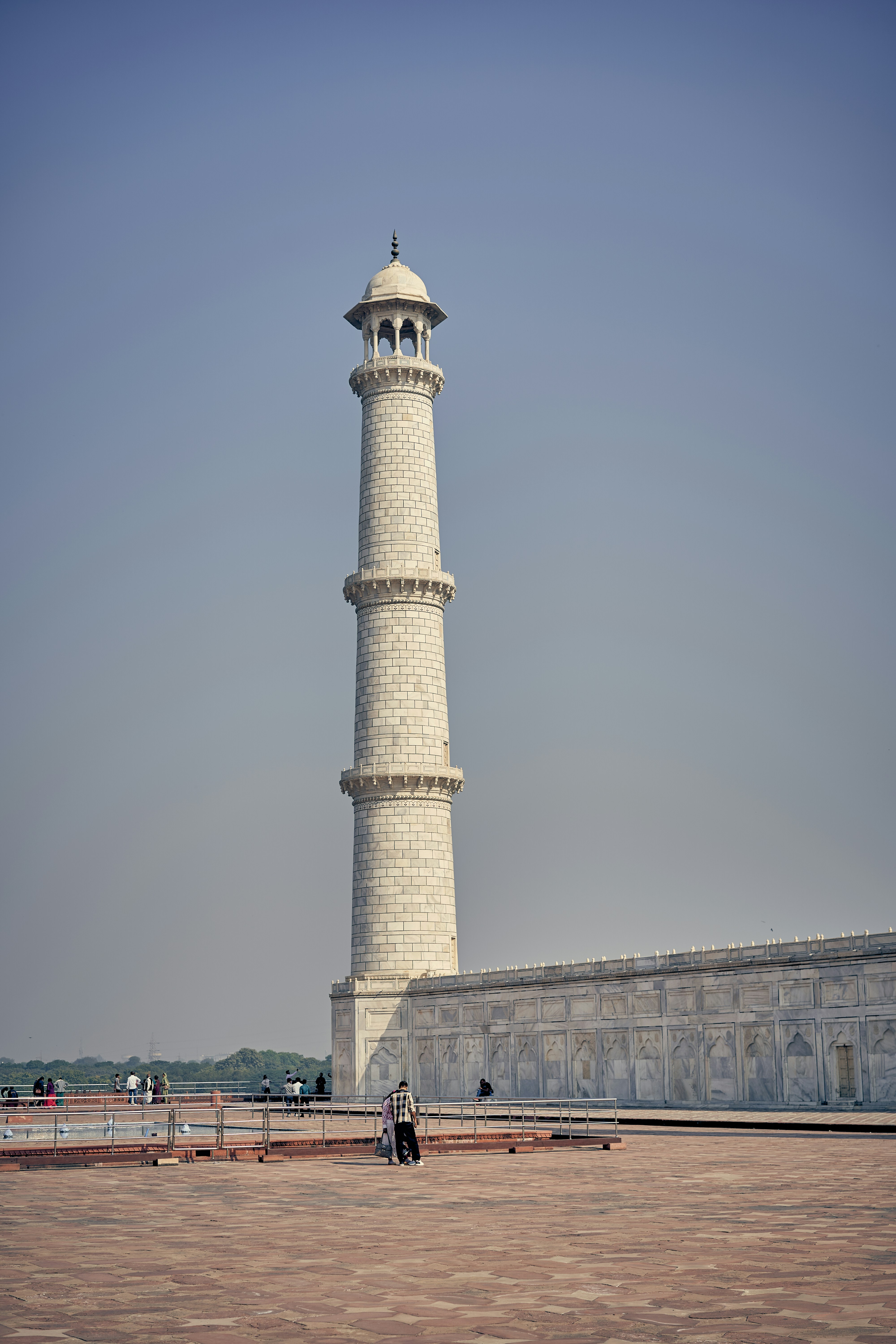 A tall white marble minaret of the Taj Mahal in Agra, India.