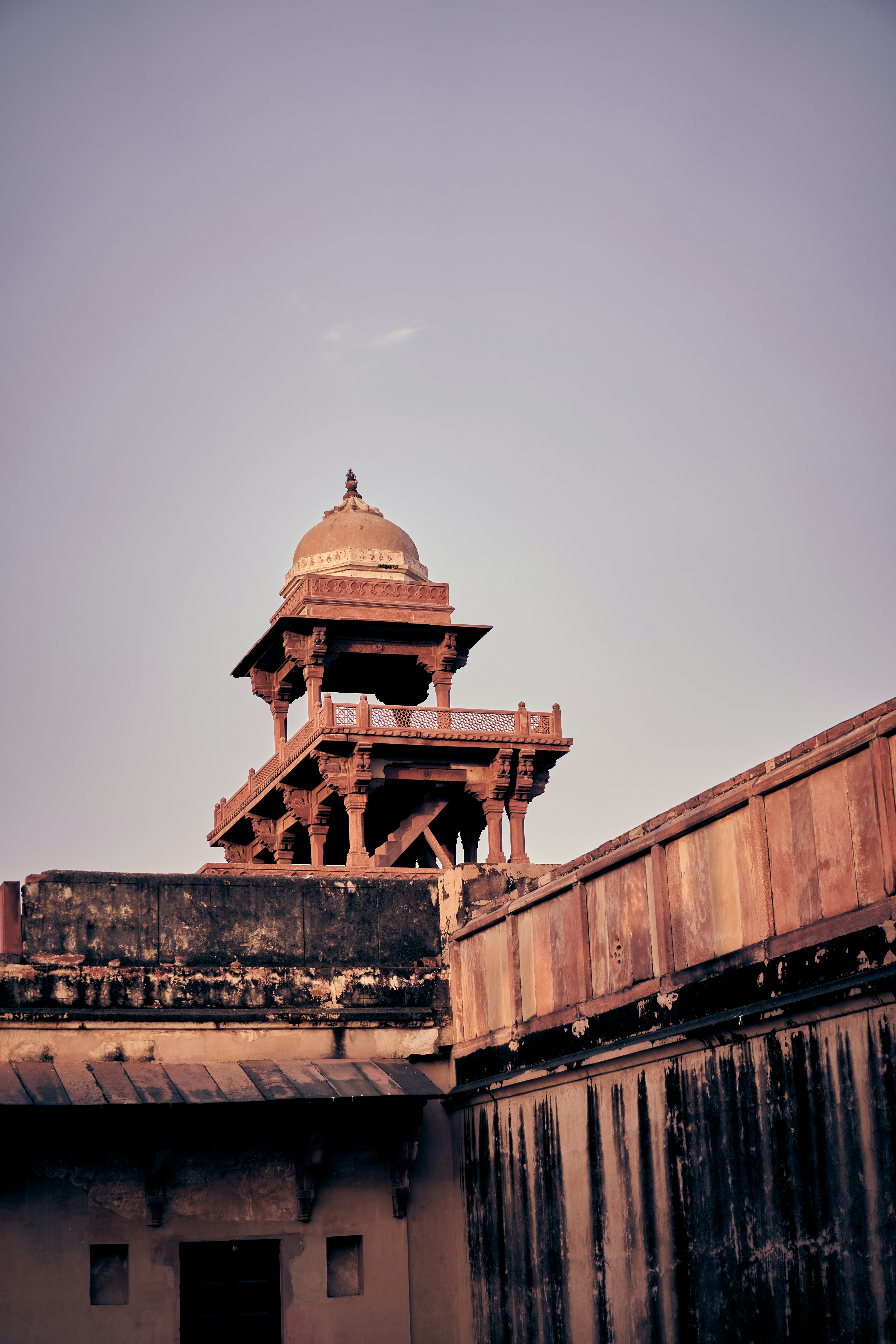A sandstone pavilion with a domed roof atop an ancient fort wall.