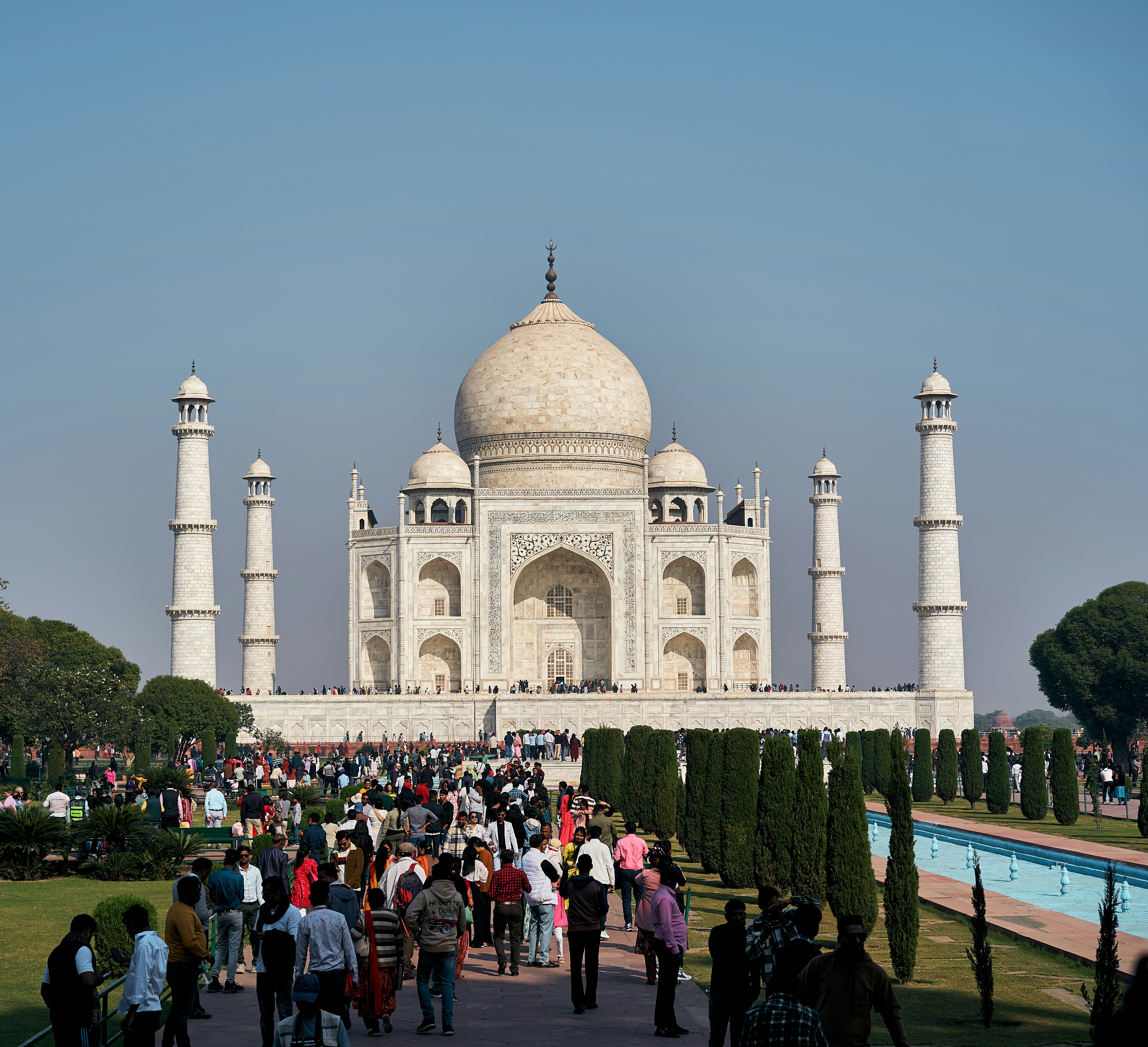 The Taj Mahal in Agra, India, with a crowd of people in the foreground.