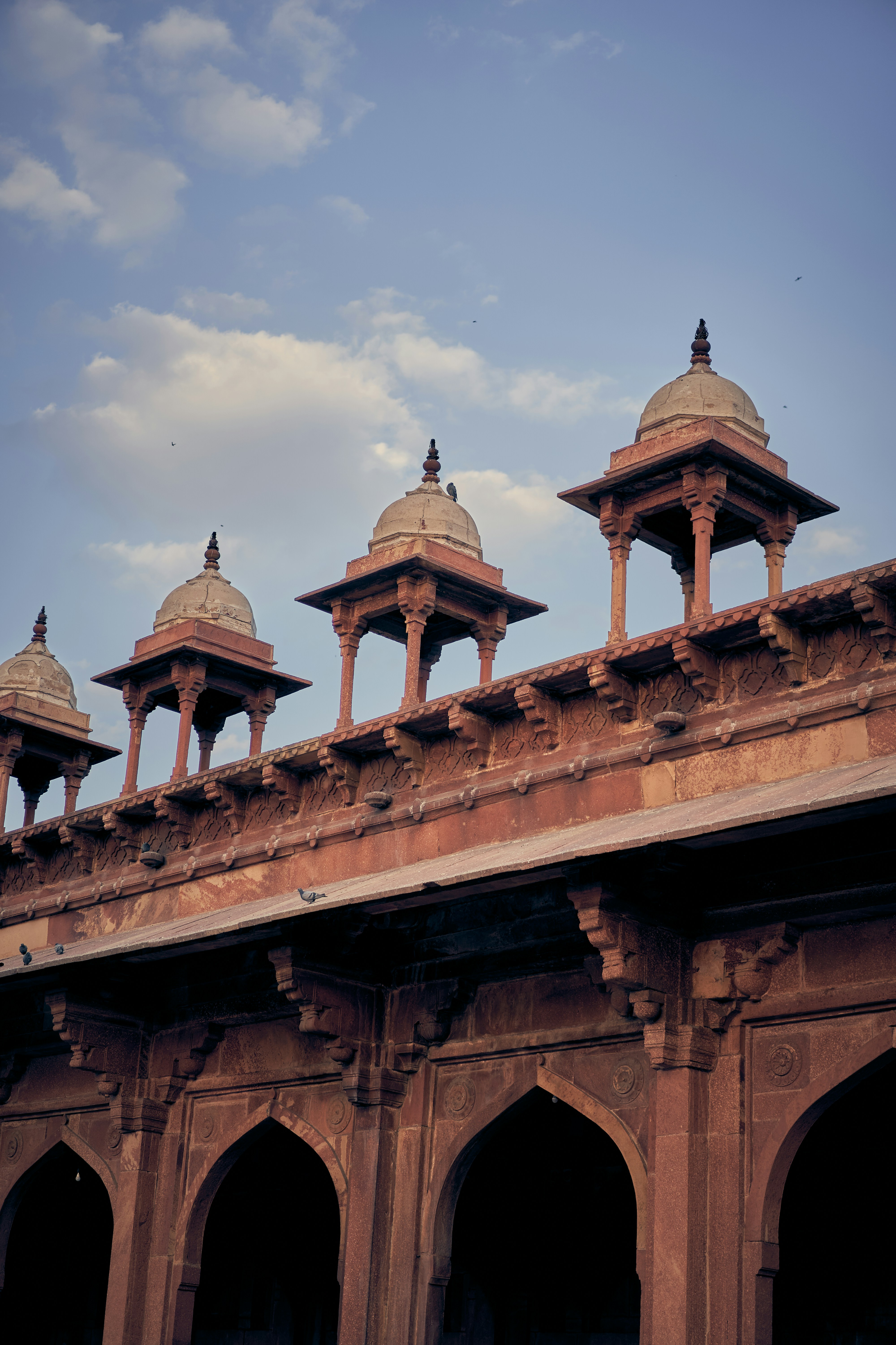 Red sandstone chhatris atop the historic architecture of Fatehpur Sikri in India.