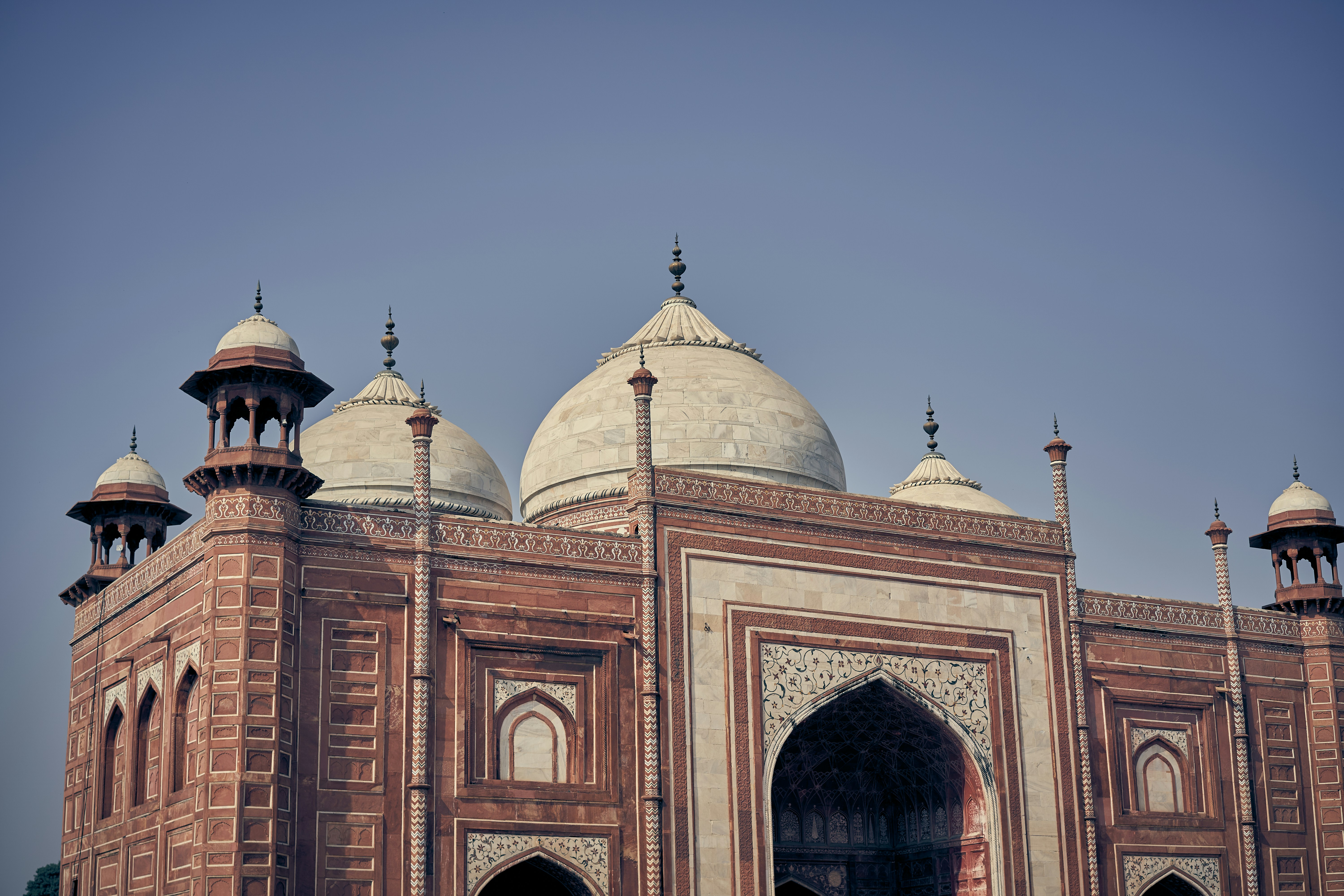 The Taj Mahal mosque building with white domes and red sandstone walls in Agra.
