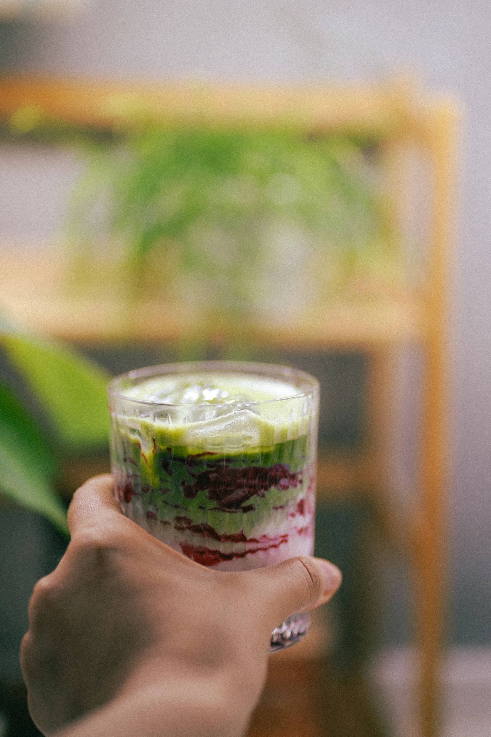 Layered iced matcha drink held inside a relaxed café